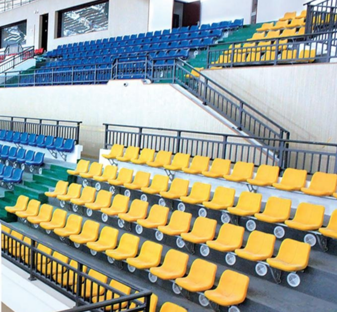 Empty stadium seating with yellow and blue chairs arranged in tiers.