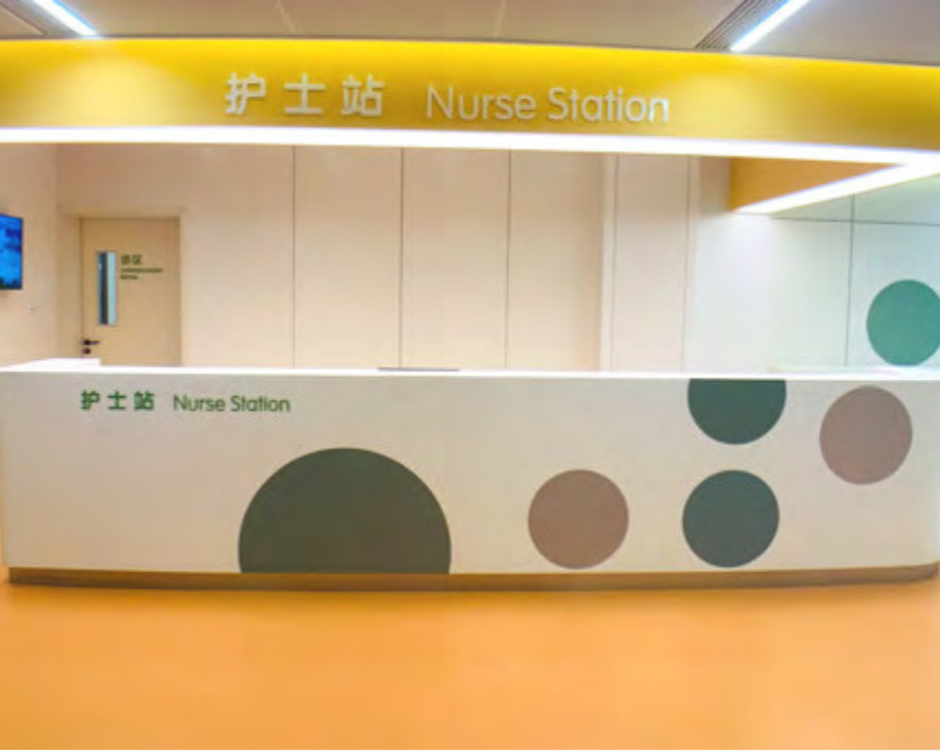 Nurse Station with yellow and white signage in English and Chinese, and a white counter decorated with large green and gray circles.