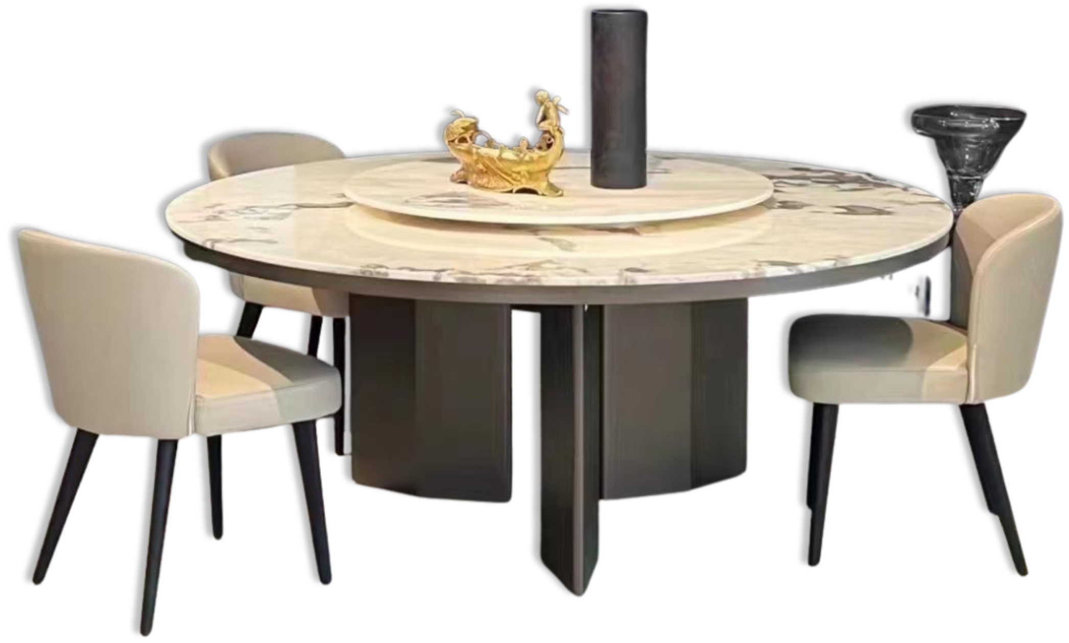 A round dining table with a marble top, surrounded by five cream-colored chairs with black legs. On the table are a large dark cylindrical vase, a gold decorative object in the shape of a boat with two human figures, and a clear glass bowl. The background is black.
