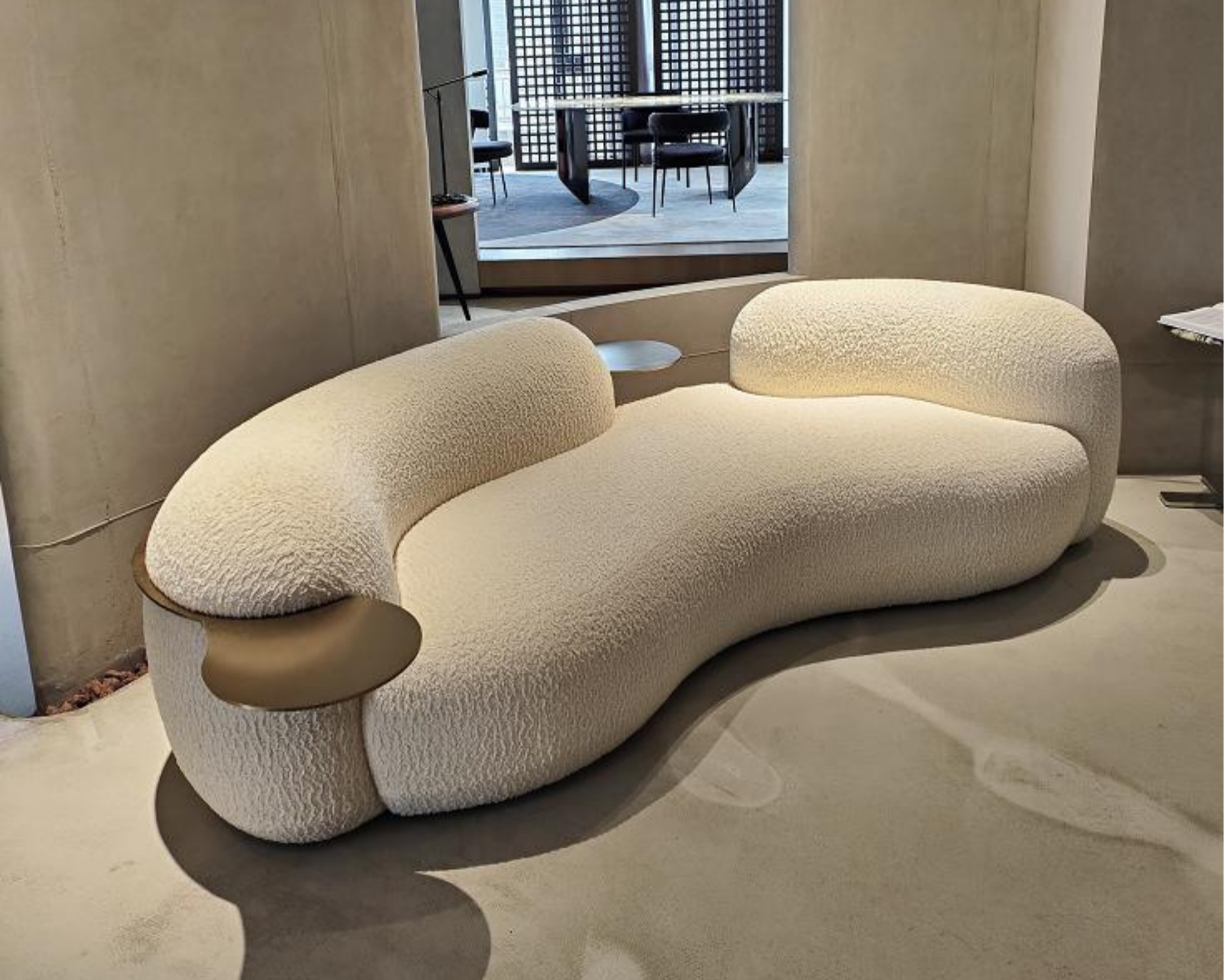 Modern beige sectional sofa with rounded edges and textured fabric in a contemporary room.