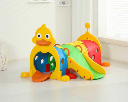 Colorful plastic children's indoor playhouse with a slide, shaped like a duck, in a room with white walls and a window.