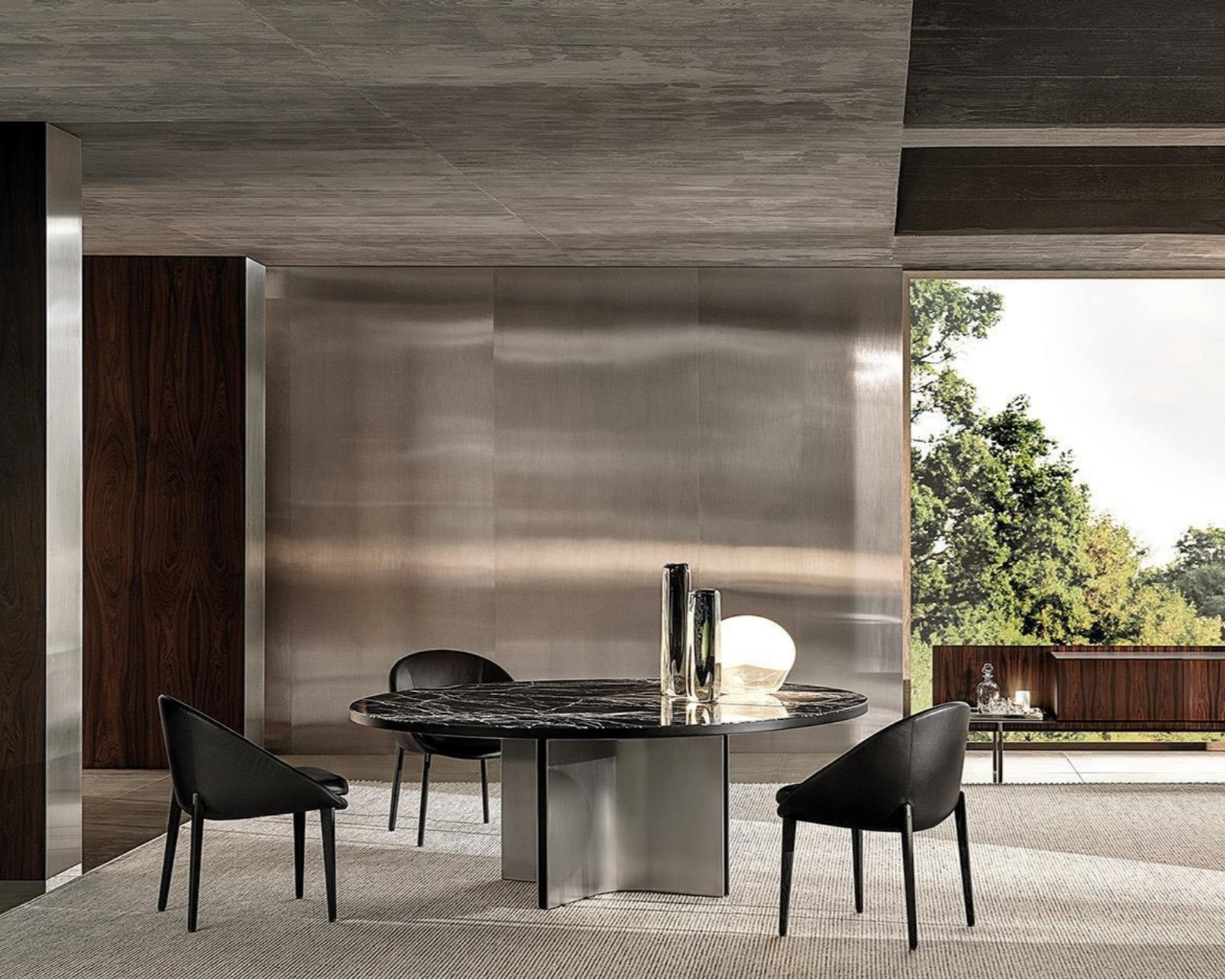 Modern dining room with a round black marble table, four black chairs, &&Vases on the table, a large window with outdoor greenery, and minimalist decor.