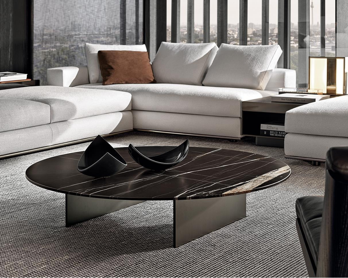 Modern living room with a large white sectional sofa, a black marble coffee table with decorative bowls, and a city view through floor-to-ceiling windows.