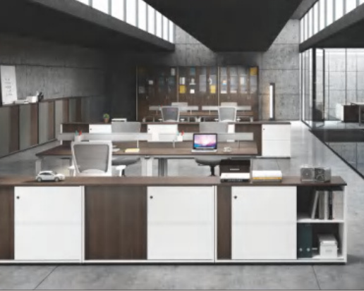 Modern office with desks, computers, and a large window wall in a contemporary building.