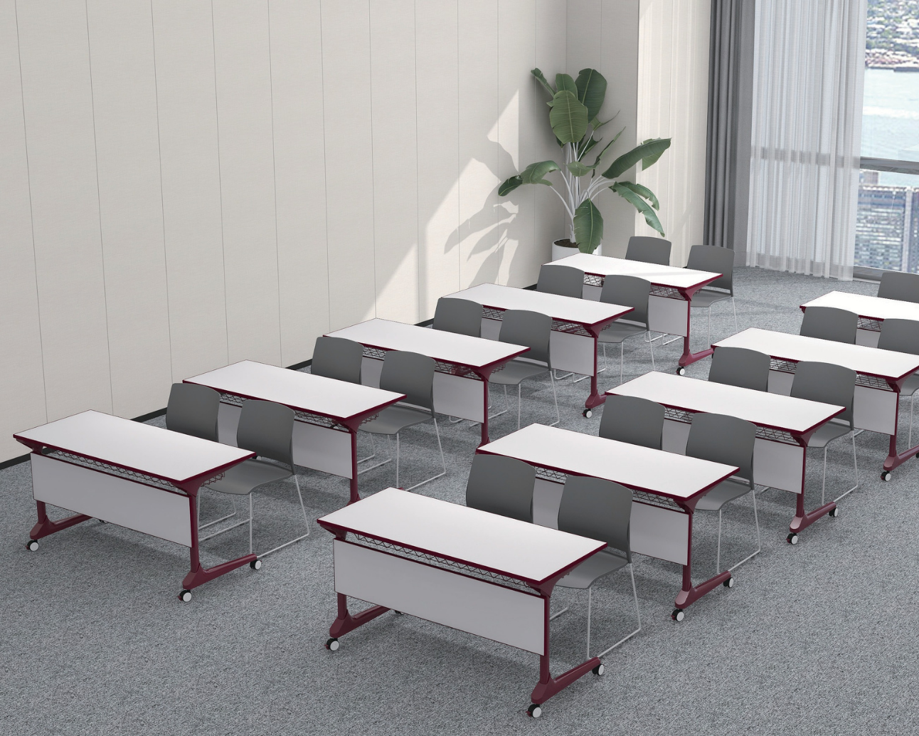 Empty classroom with rows of gray chairs and white desks near large windows with city view and a potted plant in the corner.
