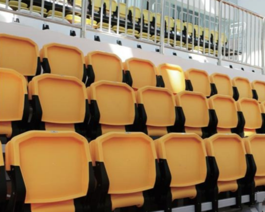 Empty yellow stadium seats in an outdoor arena.