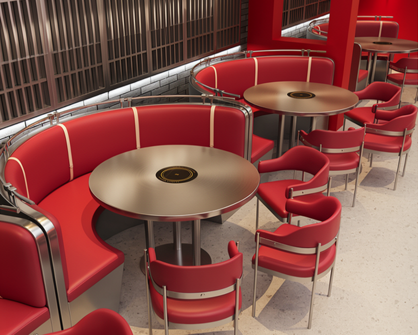 Several round tables with red cushioned chairs and banquettes in a modern restaurant or cafe.