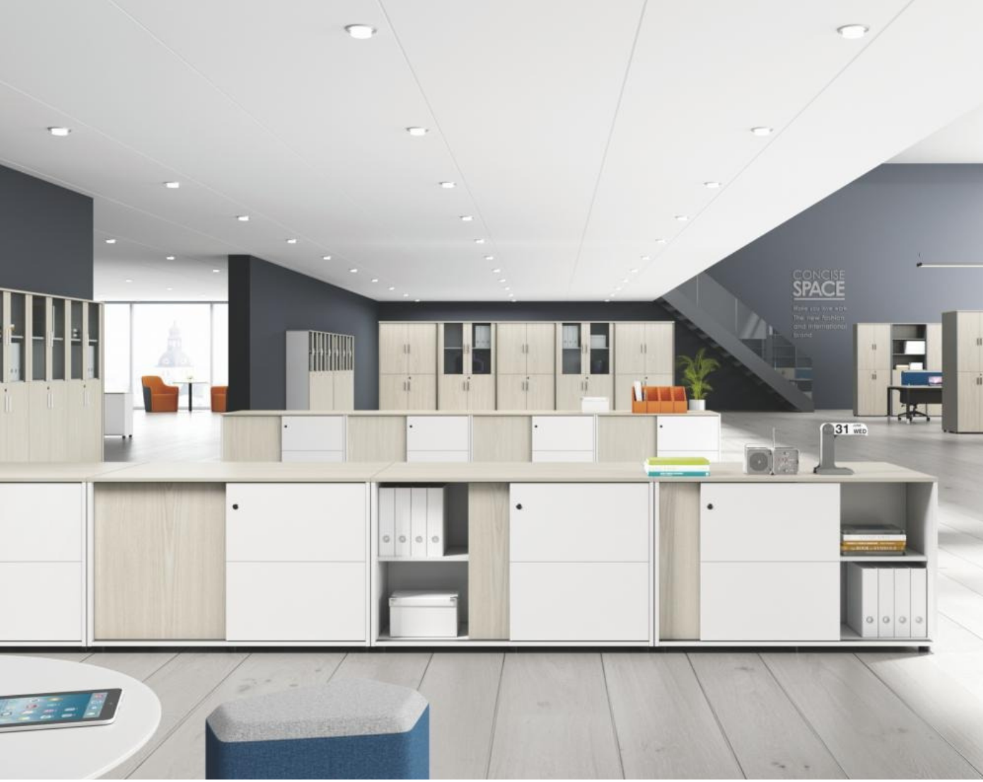 Modern office space with white desks, orange chairs, and storage lockers, featuring a staircase and large windows.