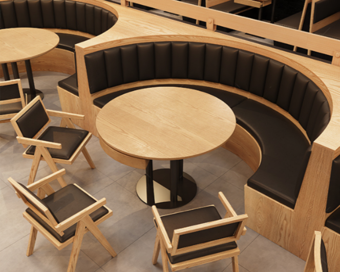Wooden round tables with black cushioned chairs and a curved booth in a modern restaurant or café.