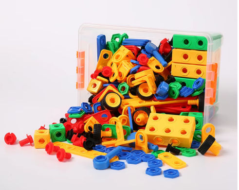 Colorful plastic construction toy pieces, including screws, nuts, and plates, spilling out of a clear storage container.