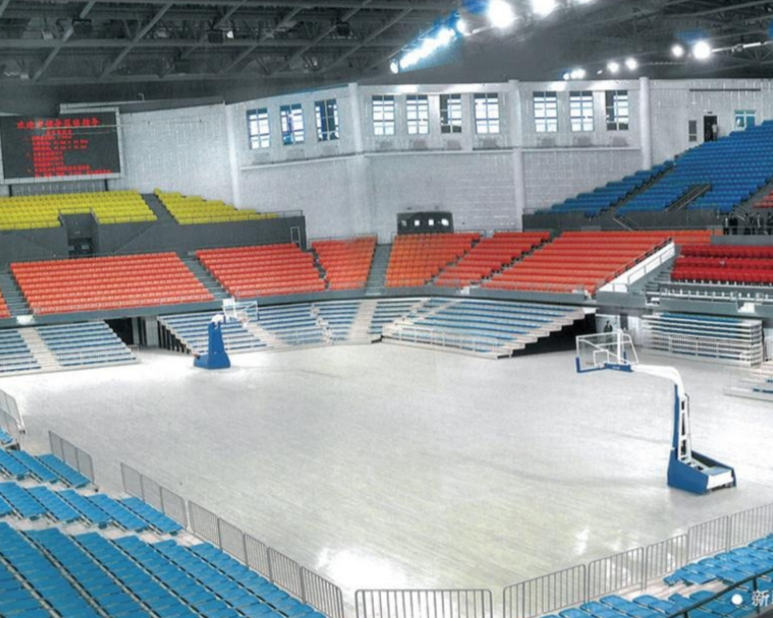 Empty indoor basketball arena with multicolored seats surrounding the court