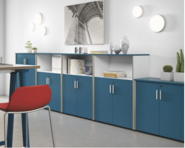 Office space with blue storage cabinets, decorative plants, artwork, and a red chair.