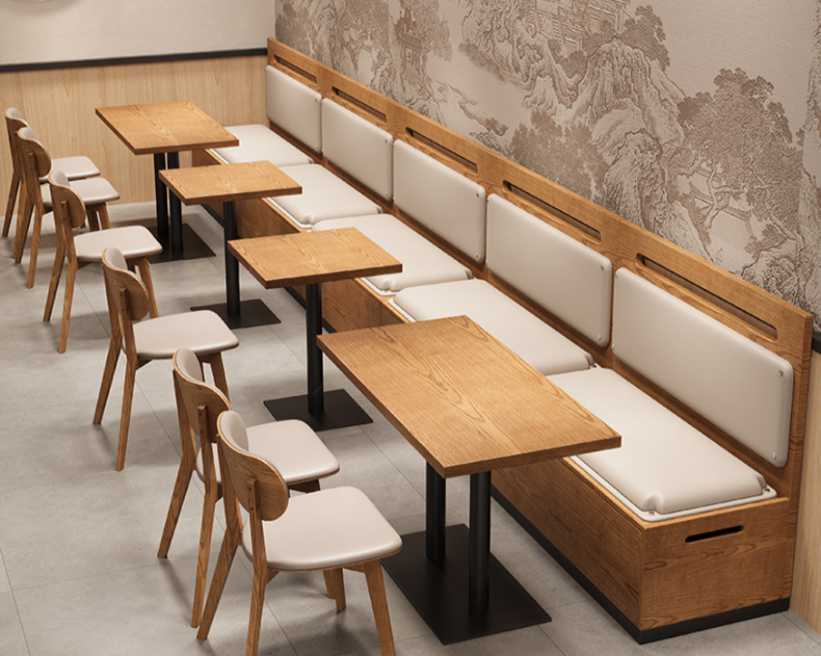 Empty restaurant booth with wooden tables, white cushioned benches, and wooden chairs with white seats against a wall with traditional Asian-style mural artwork.