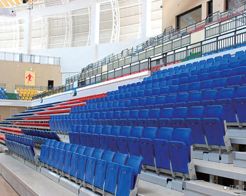 Empty stadium seats with blue, red, and yellow seats, railings, and architectural structures.