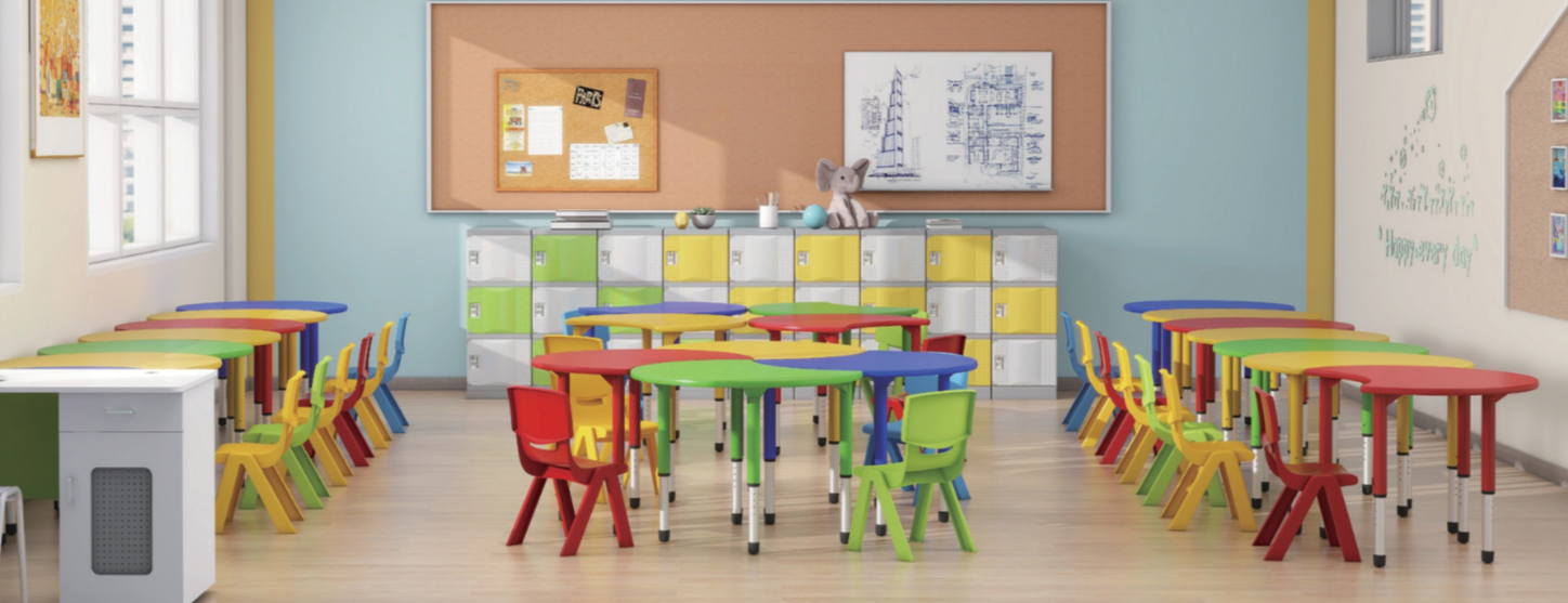 Colorful preschool classroom with small tables and chairs arranged in groups, lockers against the back wall, bulletin boards, and windows allowing natural light.