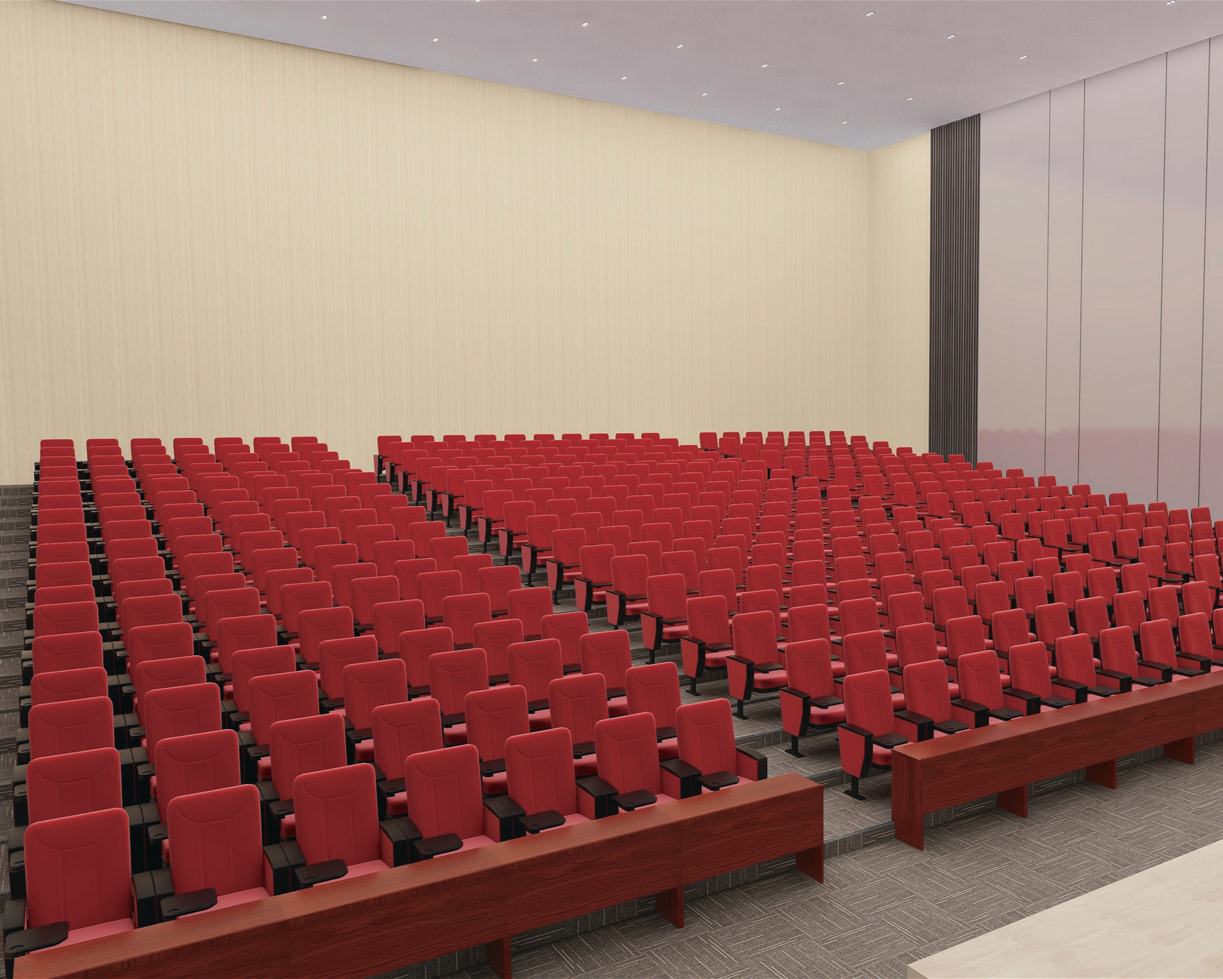 Empty auditorium with many red cushioned seats arranged in rows, wooden armrests, and a dark carpeted floor. The walls are light-colored with vertical panels, and the ceiling has small recessed lights.