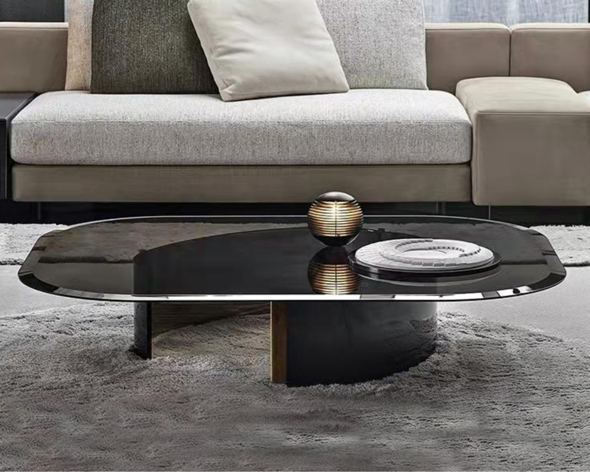 Living room with beige sofa, gray cushions, and a black coffee table with a small decorative lamp on it, placed on a light-colored rug.