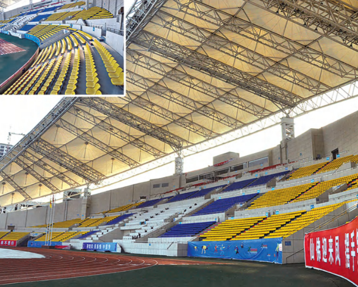 Empty stadium with yellow and blue seats, track, and covered roof, with inset showing close-up of seats.