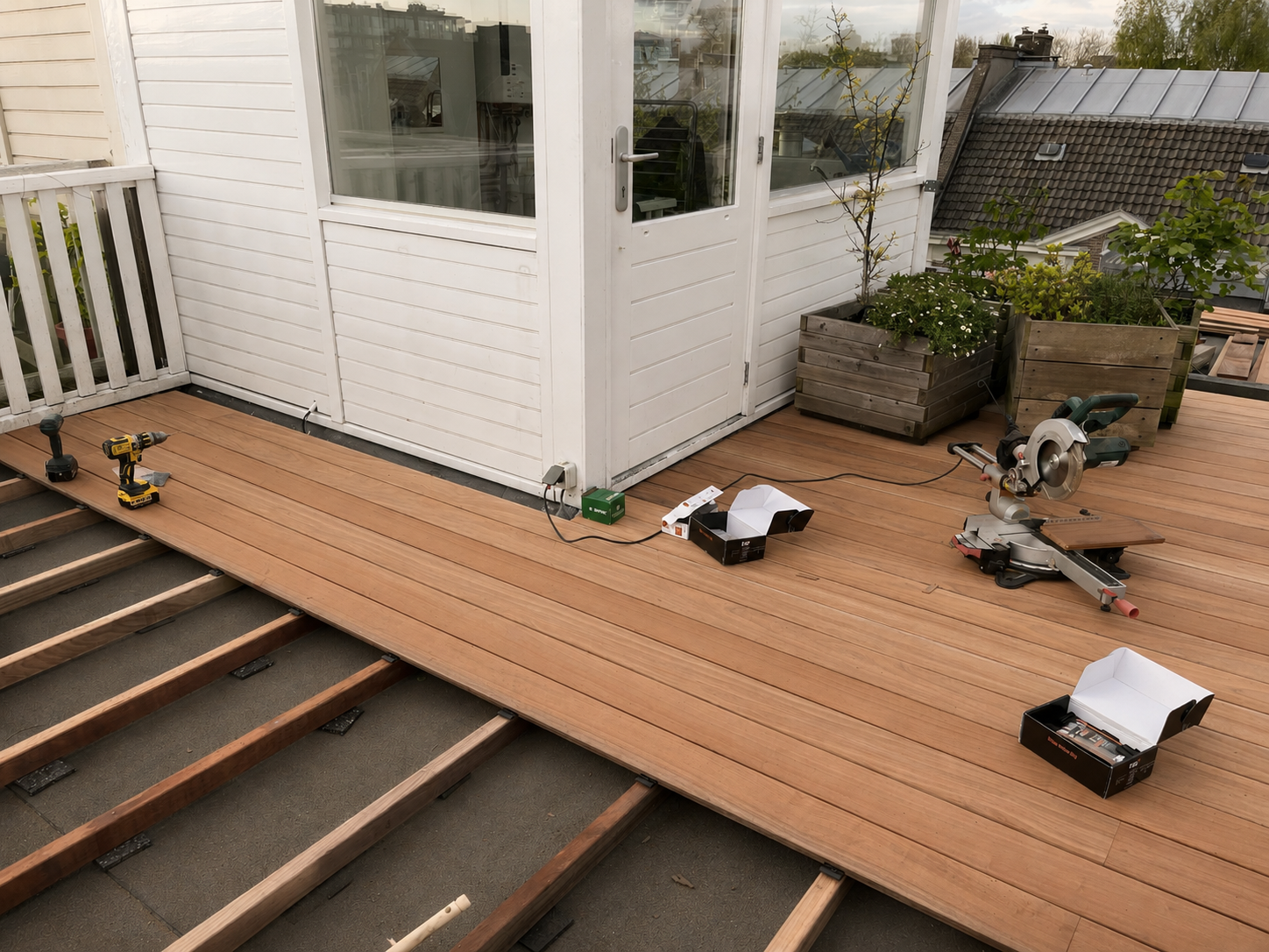 Tuinterras met houten vloer, bouwgereedschap en plantenbakken.