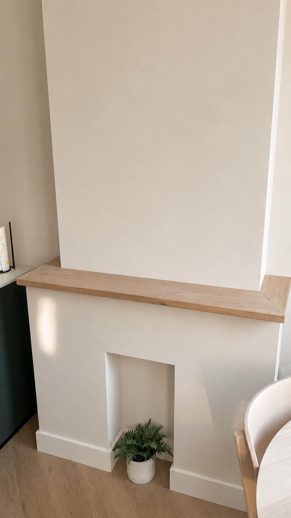 Een wand met een open nis, een houten blad en een groene plant in een witte pot aan de onderkant.