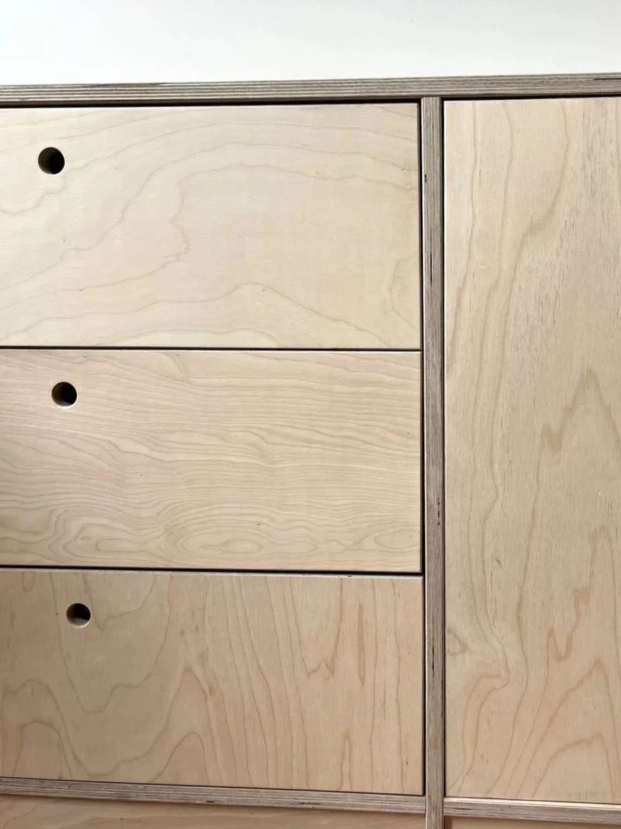 Een houten ladekast met drie lades en een kastdeur, alles gemaakt van lichtkleurig hout.
