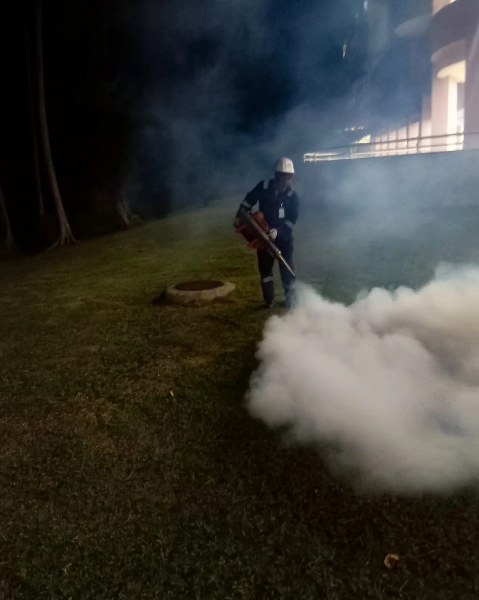 Professional mosquito fogging service carried out outdoors at night near the jungle in Brunei.
