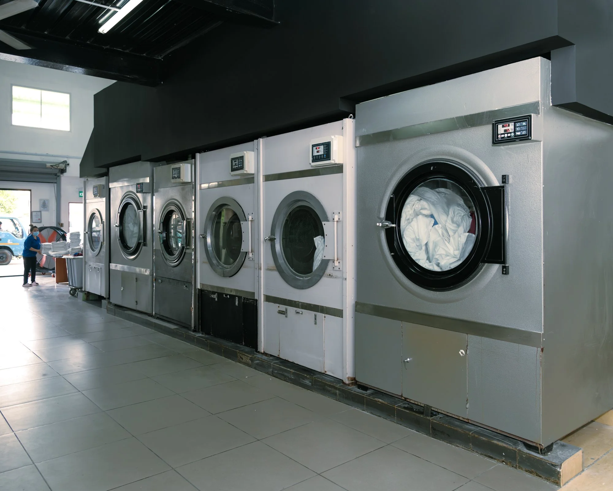 A row of commercial laundry machines being operated on in Brunei