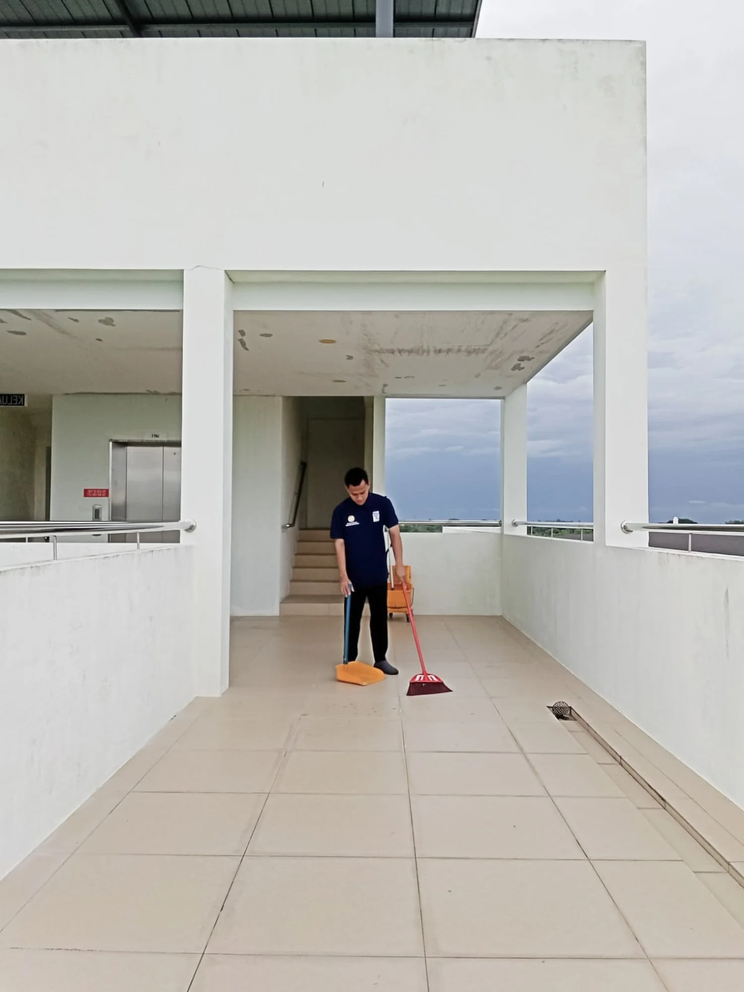 Professional janitorial cleaning and sweeping taking place outside at the corridor of a building in Brunei.