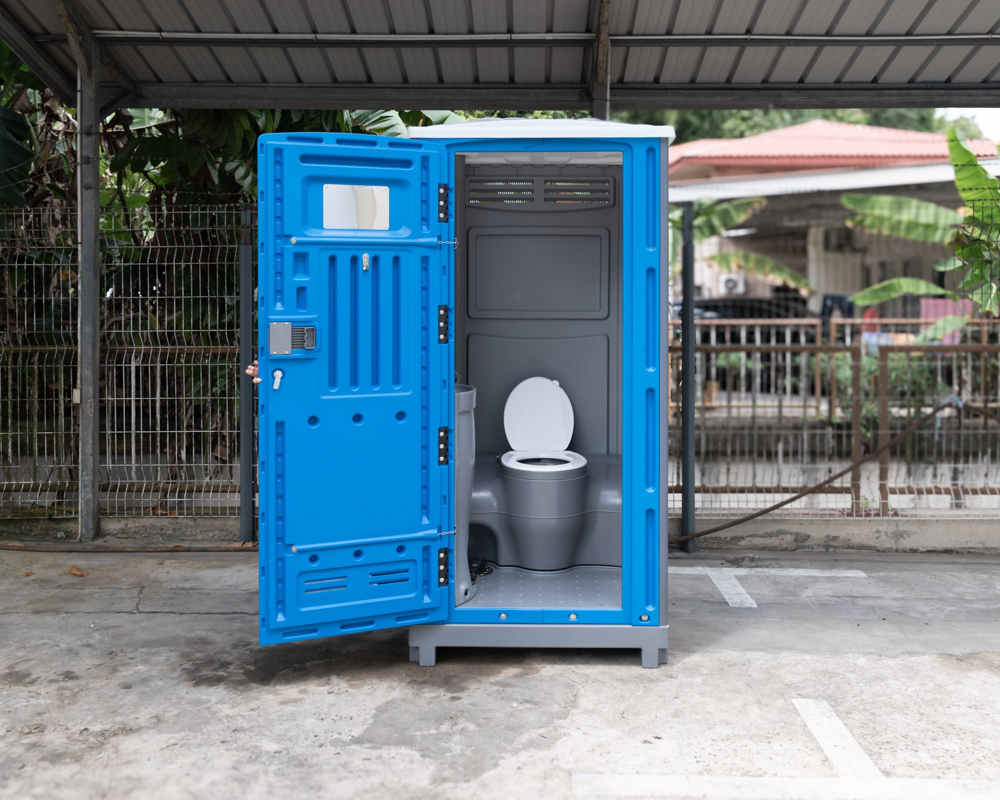 A blue portable toilet for rent, positioned in an outdoor area in Brunei.