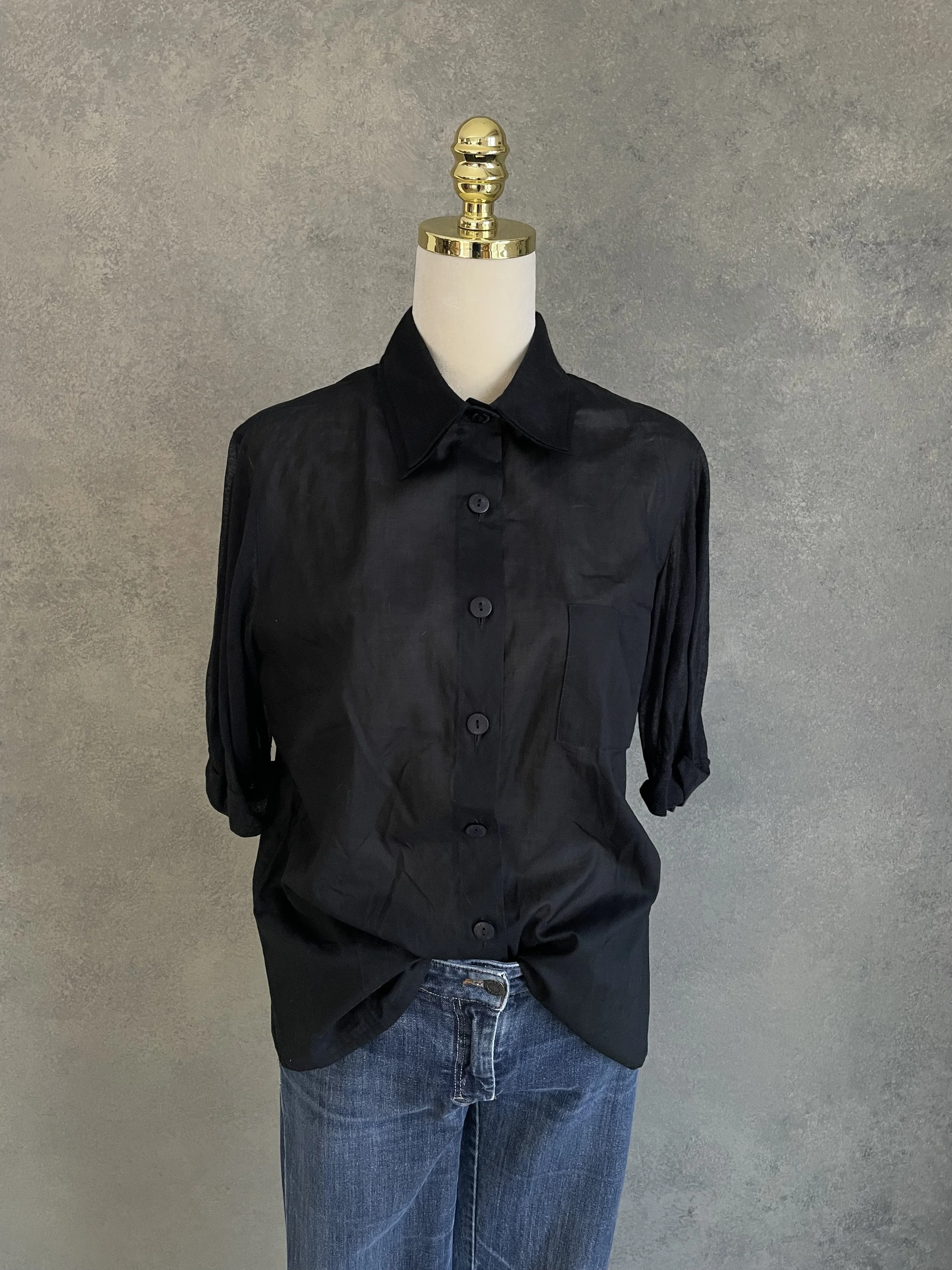 Kathleen Madden black blouse styled on a mannequin, showcasing the clean, minimalist silhouette and professional drape