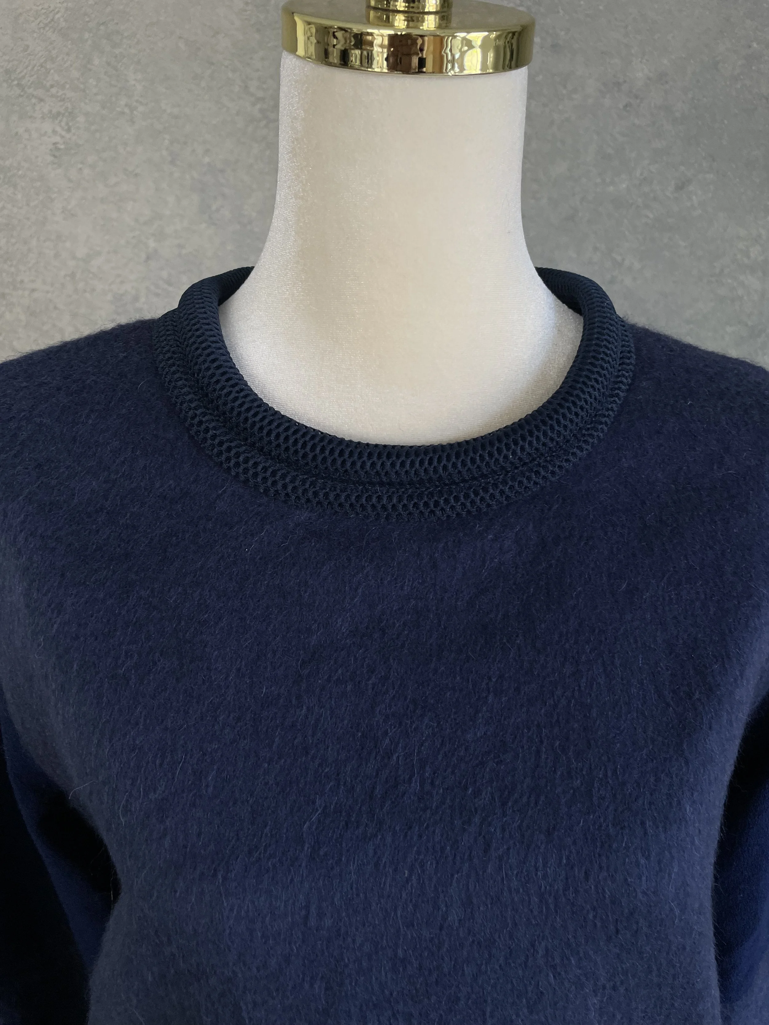 Detailed close-up of the ribbed crew neckline on the deep navy Vladimir Karaleev sweater.