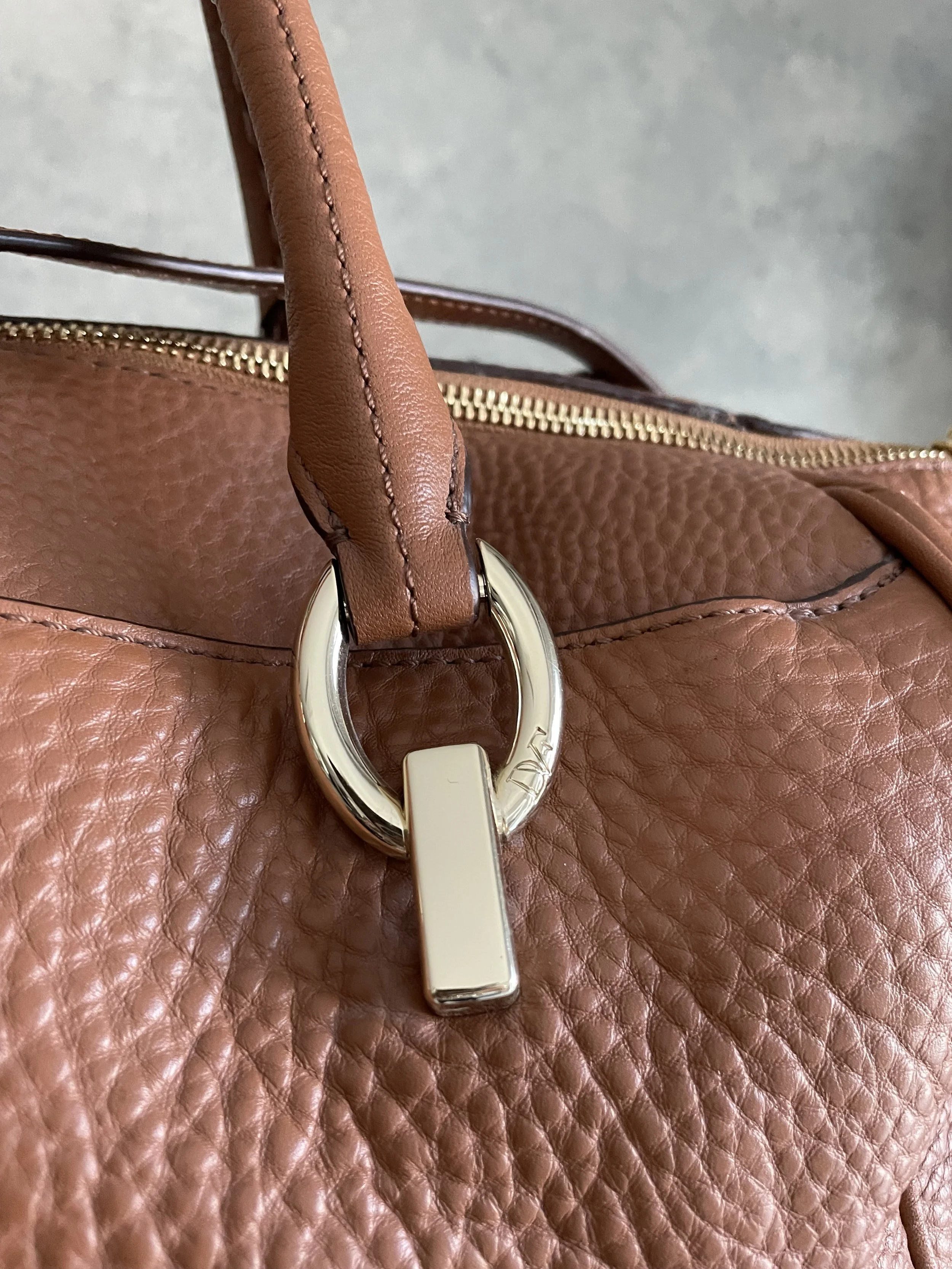 Close-up of the gold-tone ring hardware and handle connection on the DVF bag.