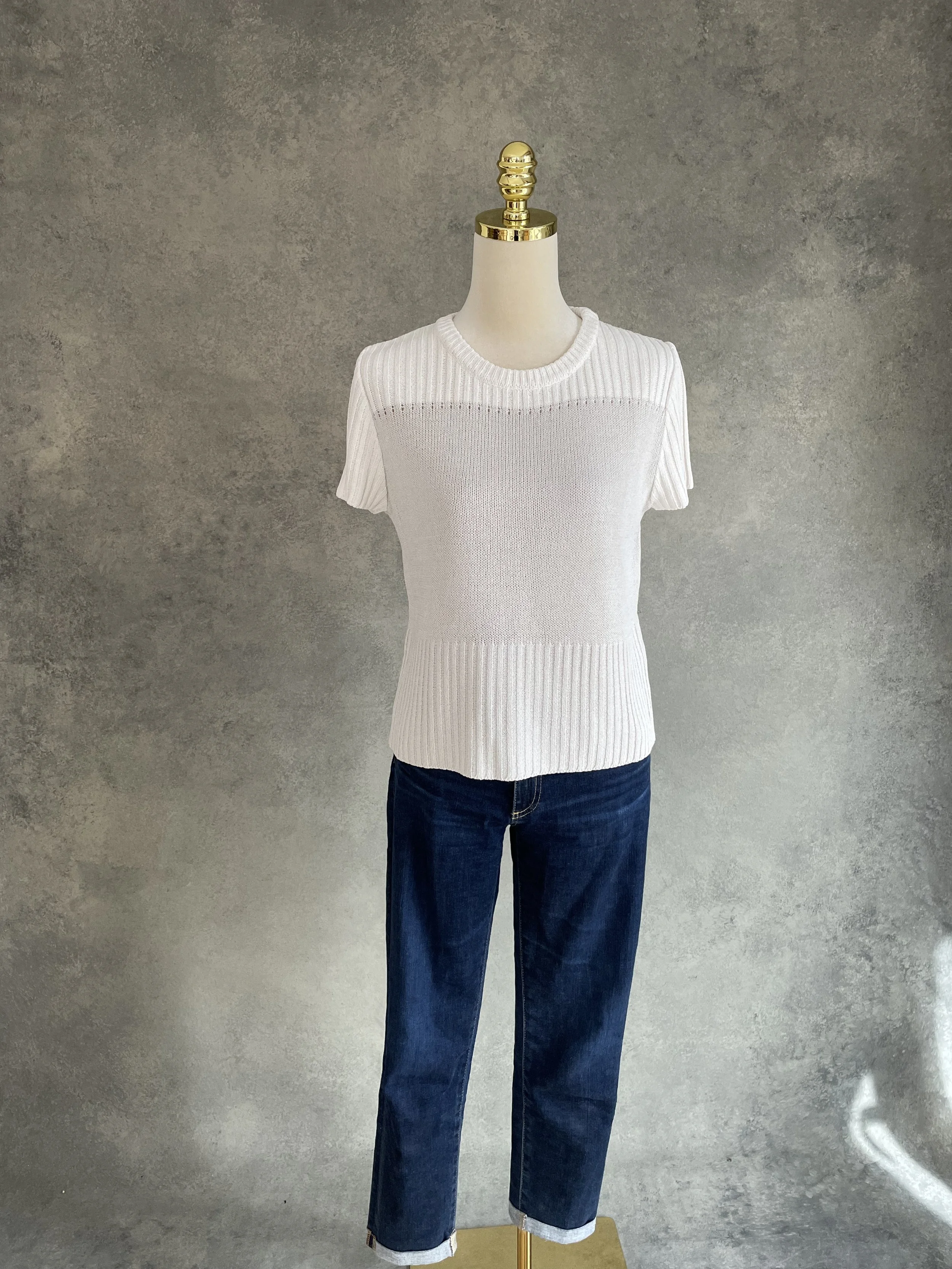Full view of a beige and silver Natan knit top on a mannequin against a grey textured background.