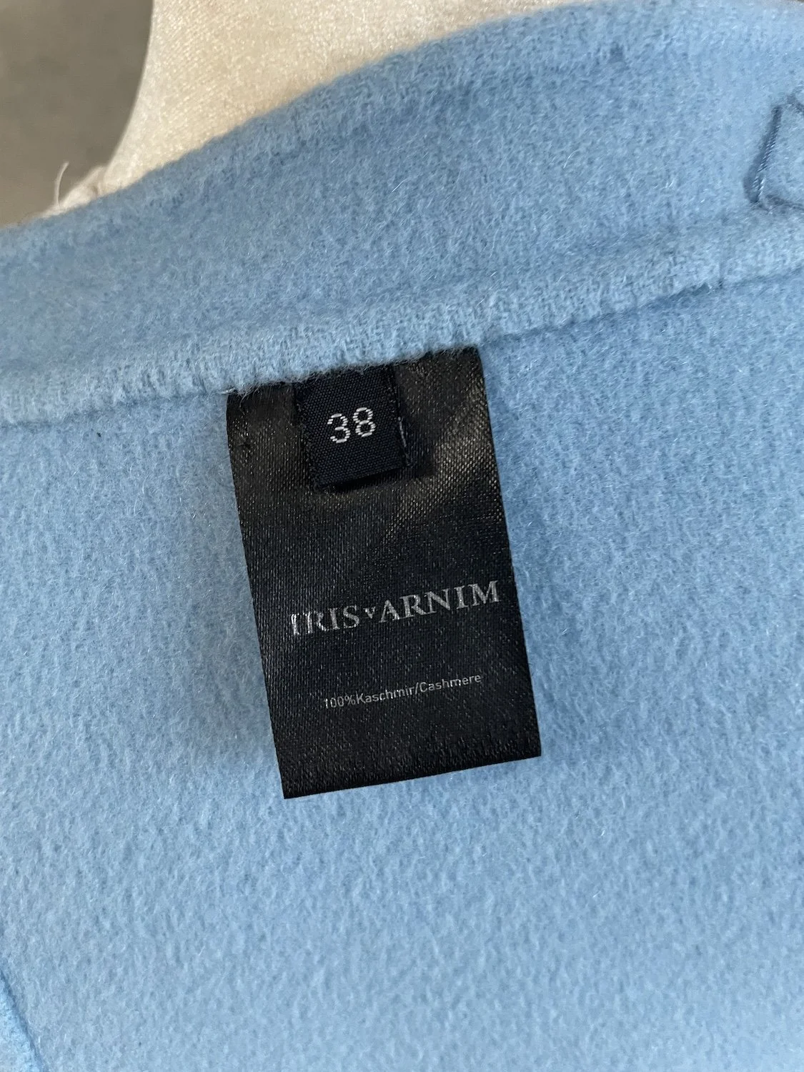 Close-up of the black woven 'IRIS VON ARNIM' brand label showing size 38 and 100% Kaschmir/Cashmere composition