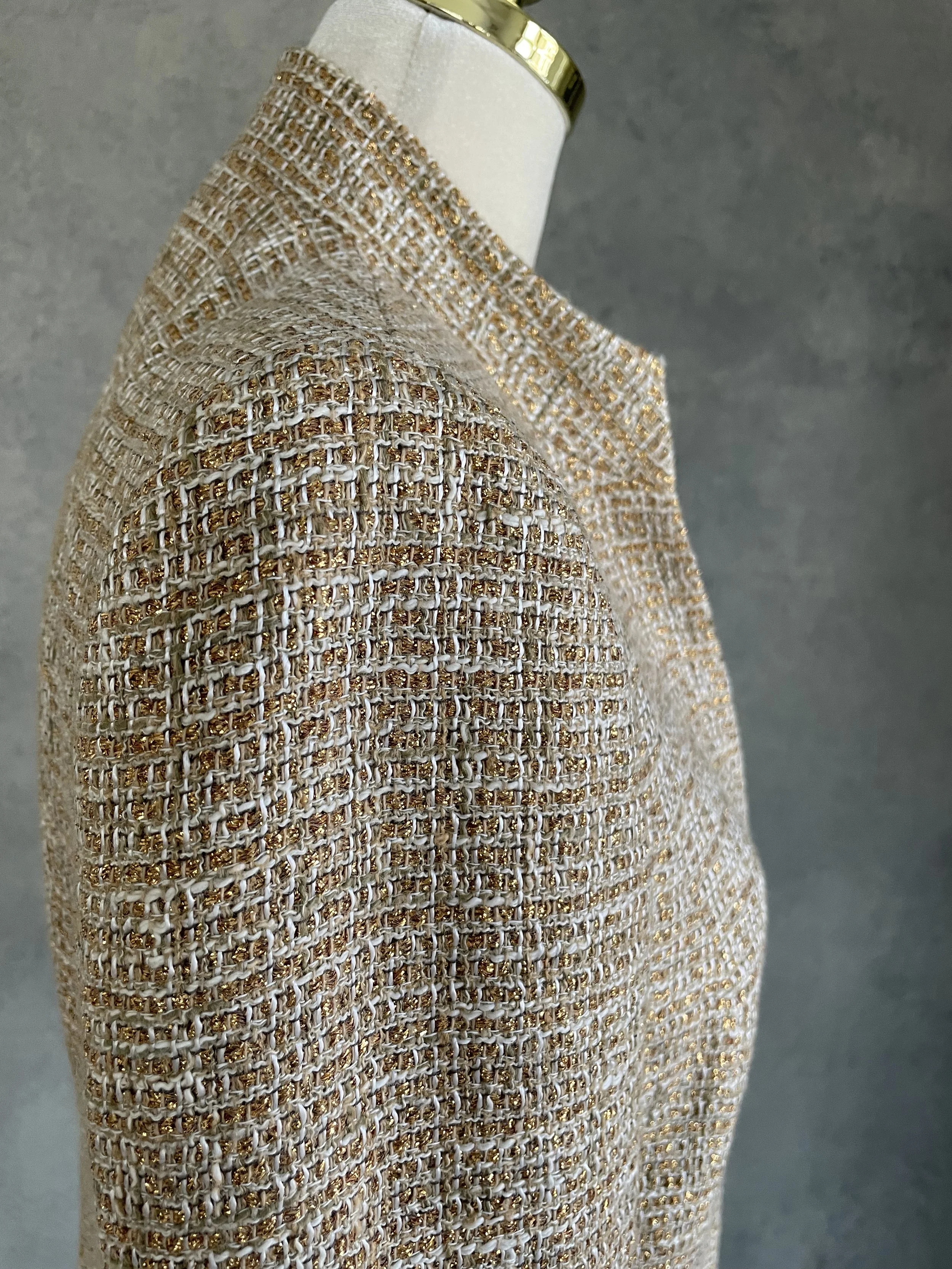 Close-up of the shoulder and sleeve construction on the golden tweed coat.