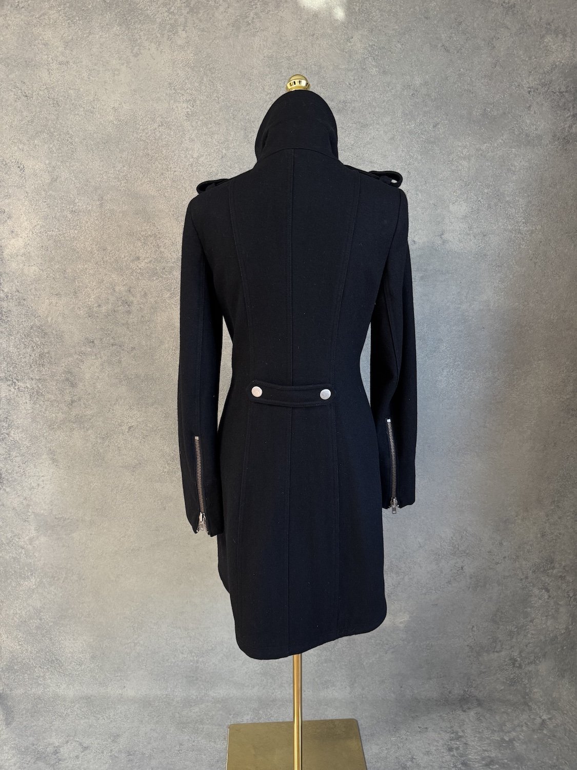 Rear view of the coat, highlighting the structured panel seams and back button tab.