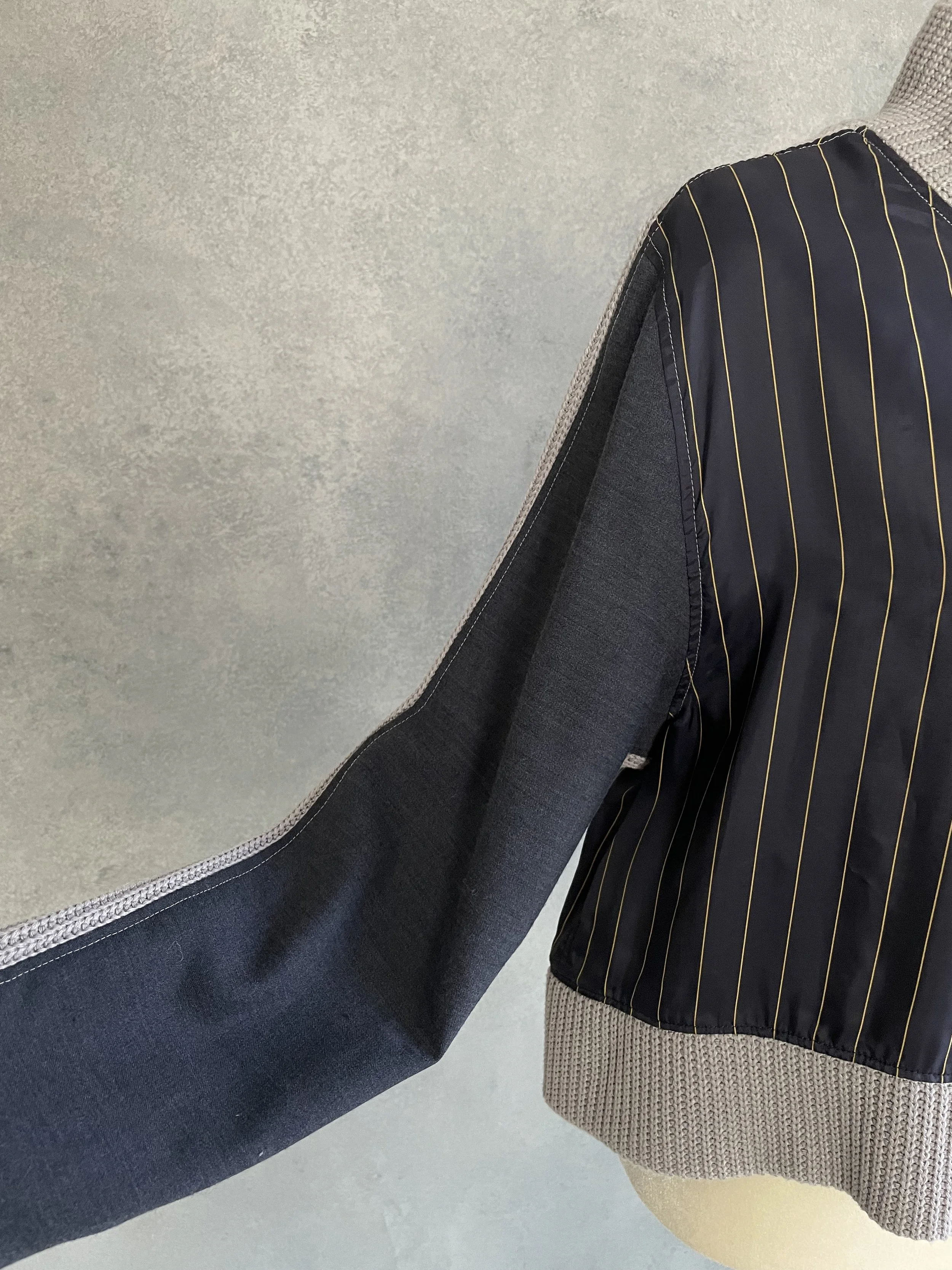 Detail view of the hybrid construction showing the transition between the pinstriped navy panel and the grey knit sleeve.