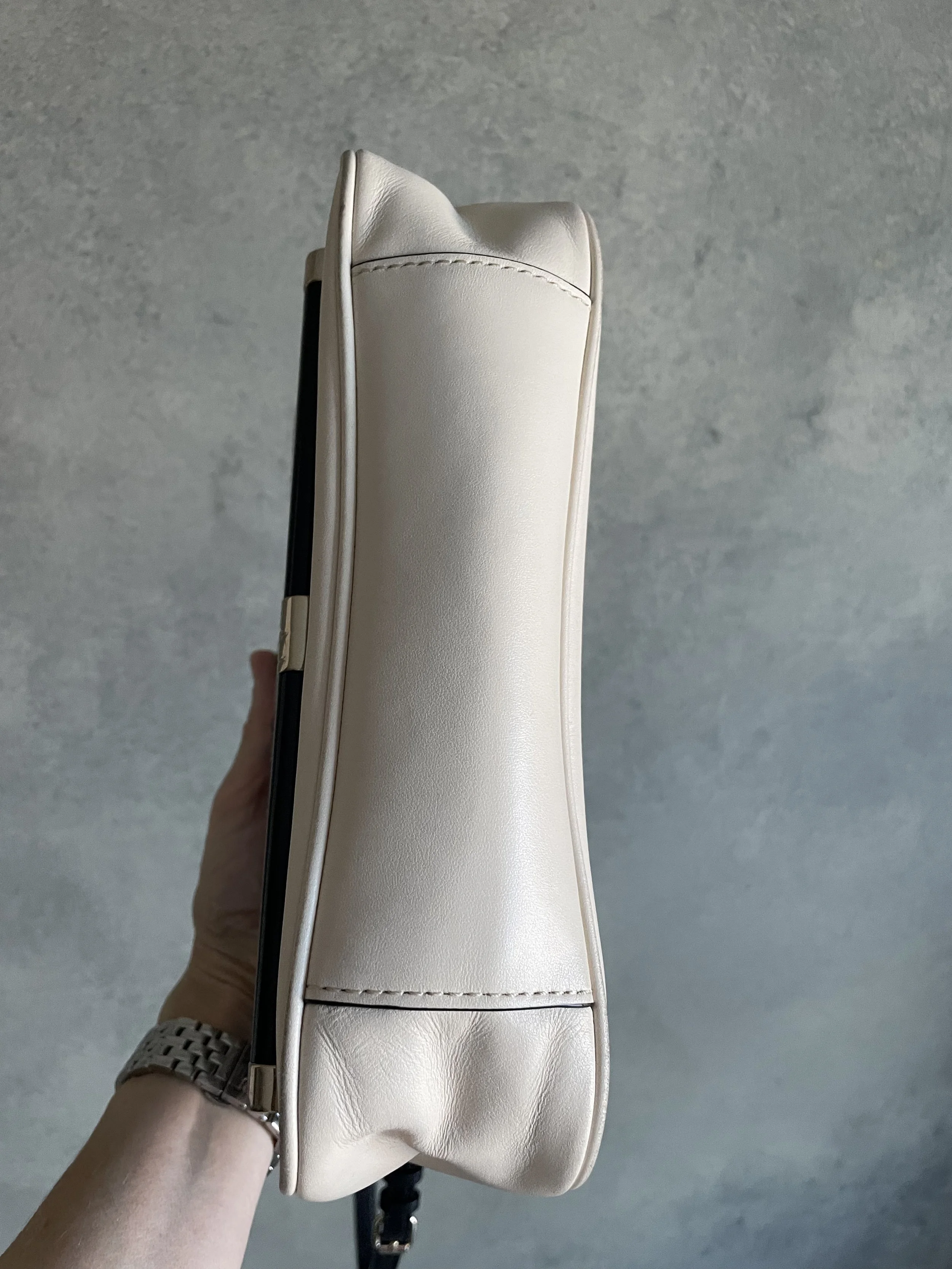 Side profile of the DVF 440 handbag, illustrating the clean, minimalist lines of the cream leather gussets.