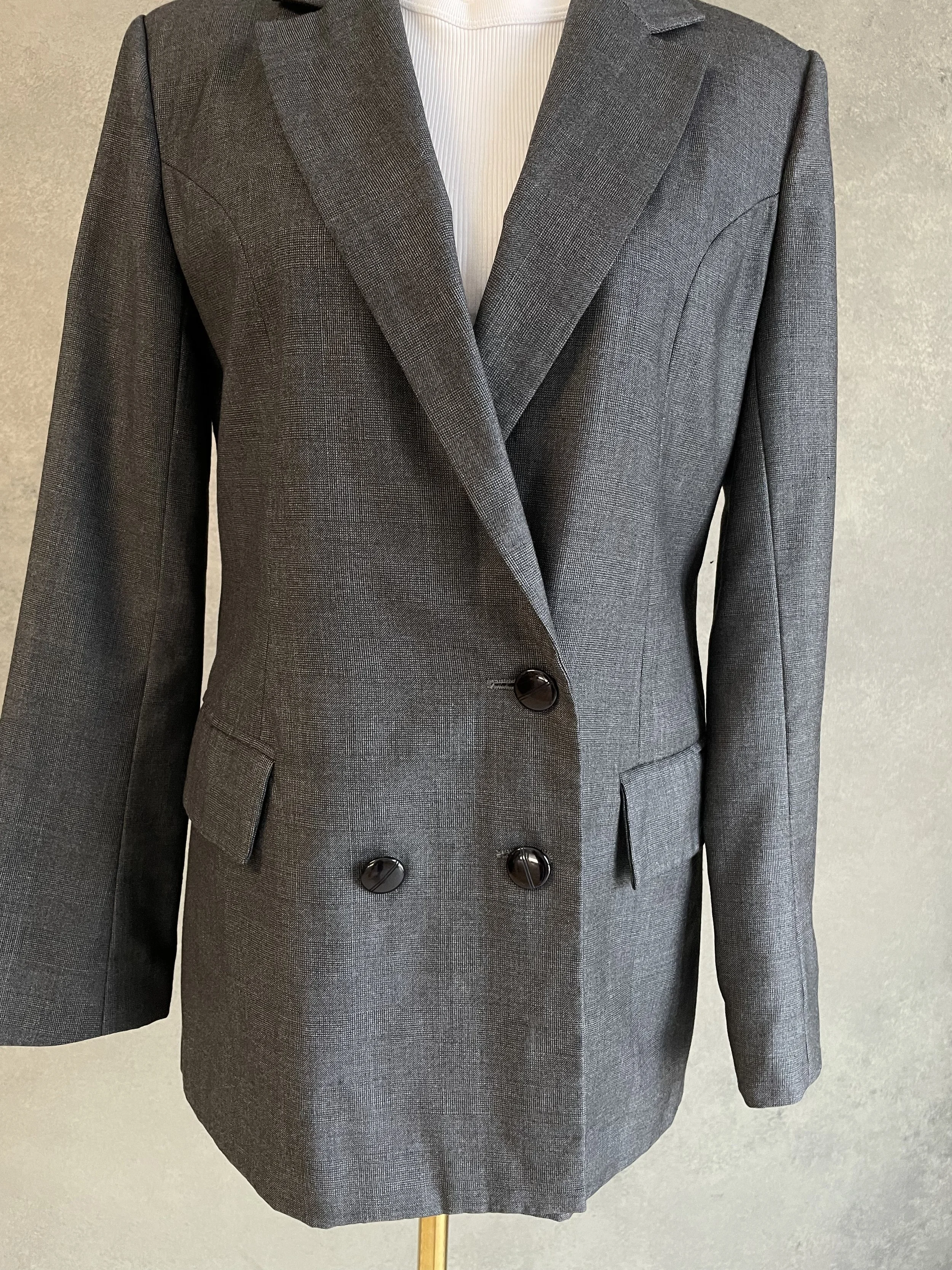 Close-up front view of the blazer's double-breasted button detailing, structured lapels, and flapped side pockets.