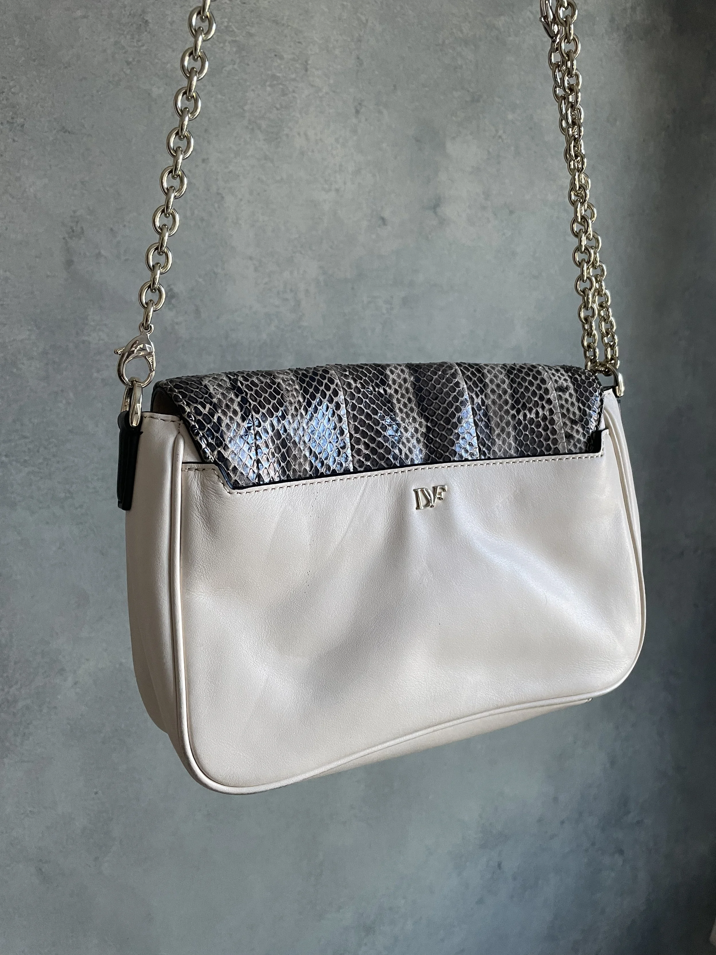 Macro shot of the DVF logo hardware and snakeskin texture on the envelope flap.