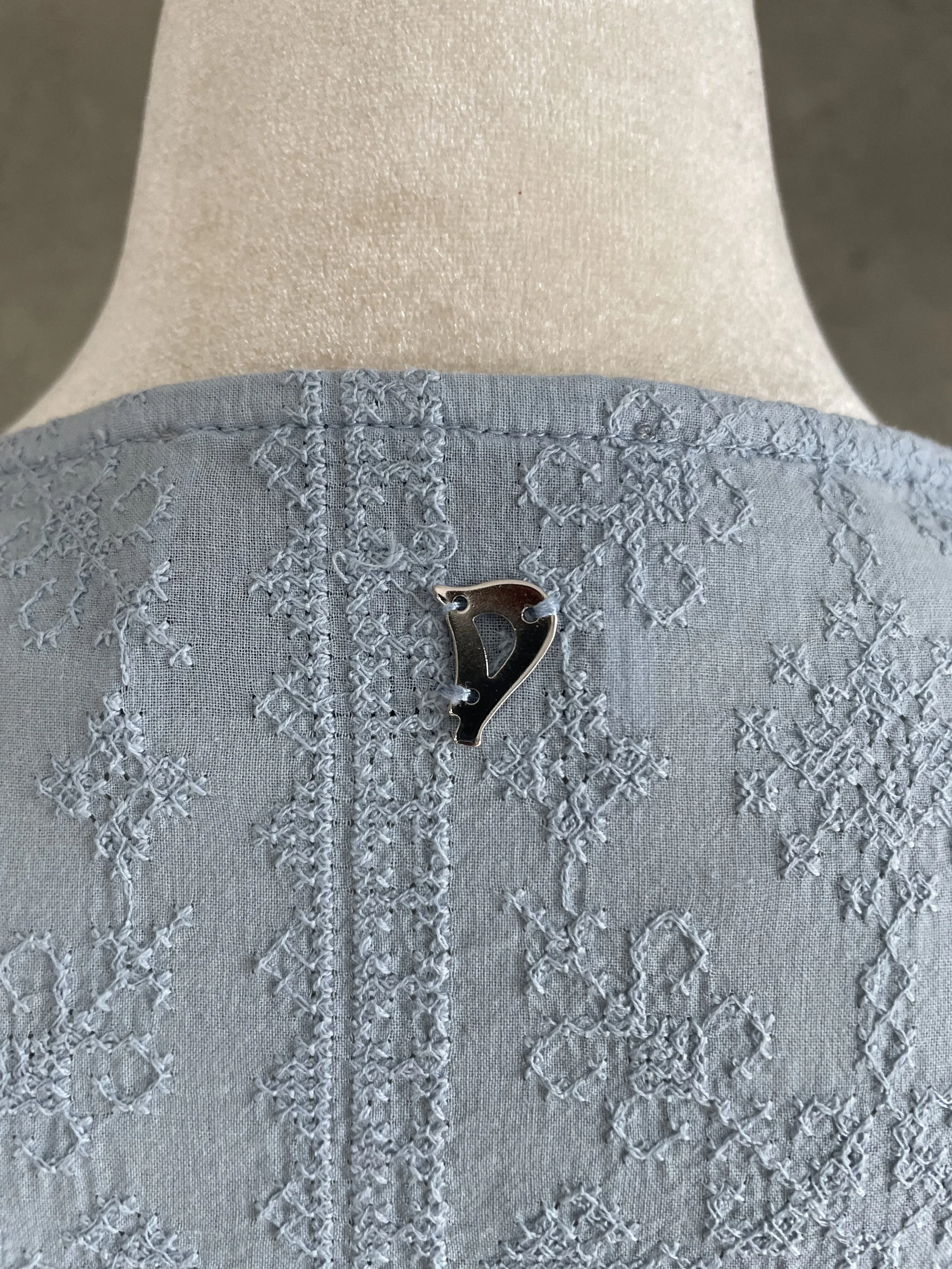 Close-up of the silver 'D' logo detail on the back neckline."
