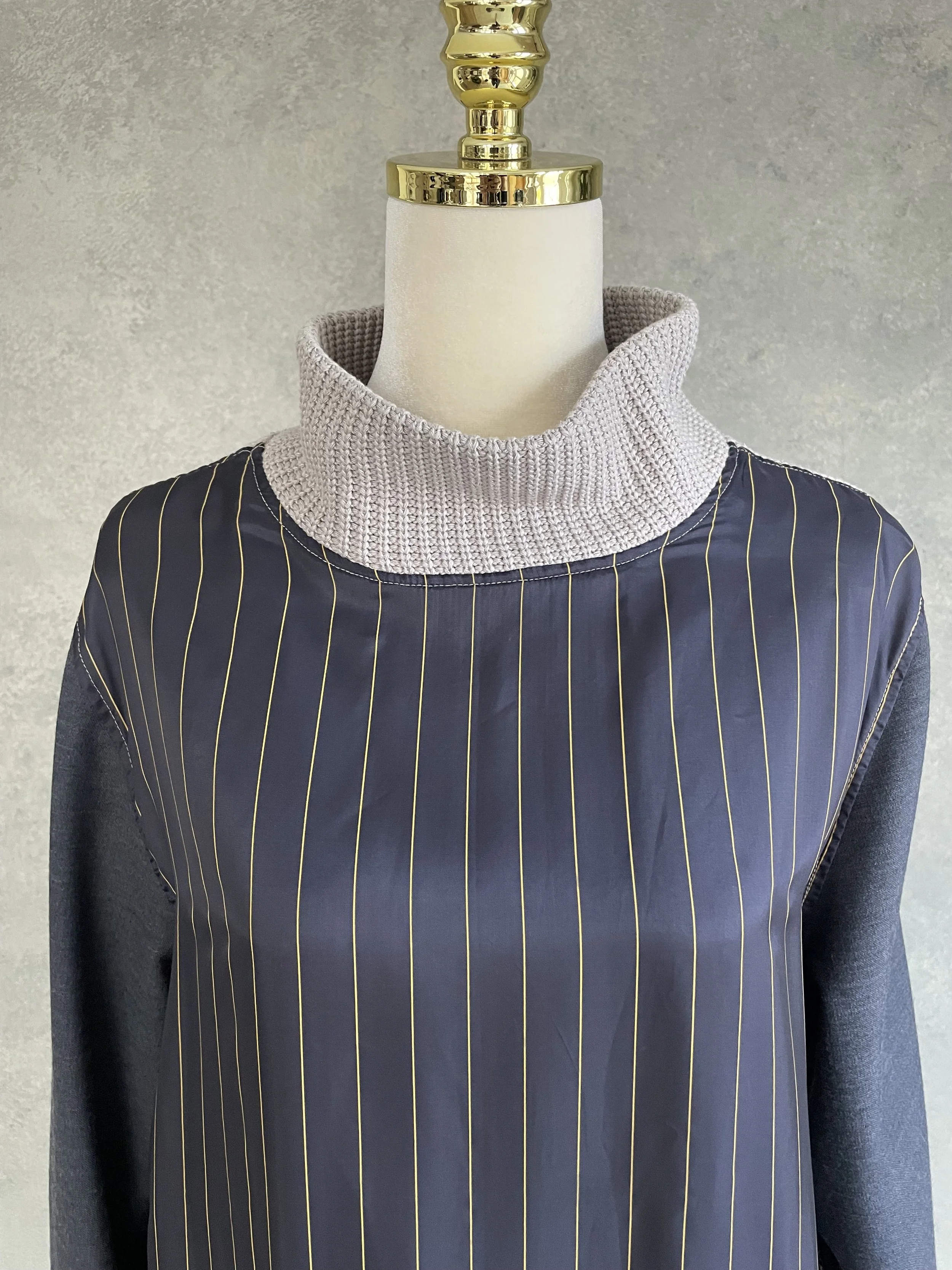 Close-up of the grey chunky knit turtleneck collar on a Vladimir Karaleev pinstripe hybrid sweater.