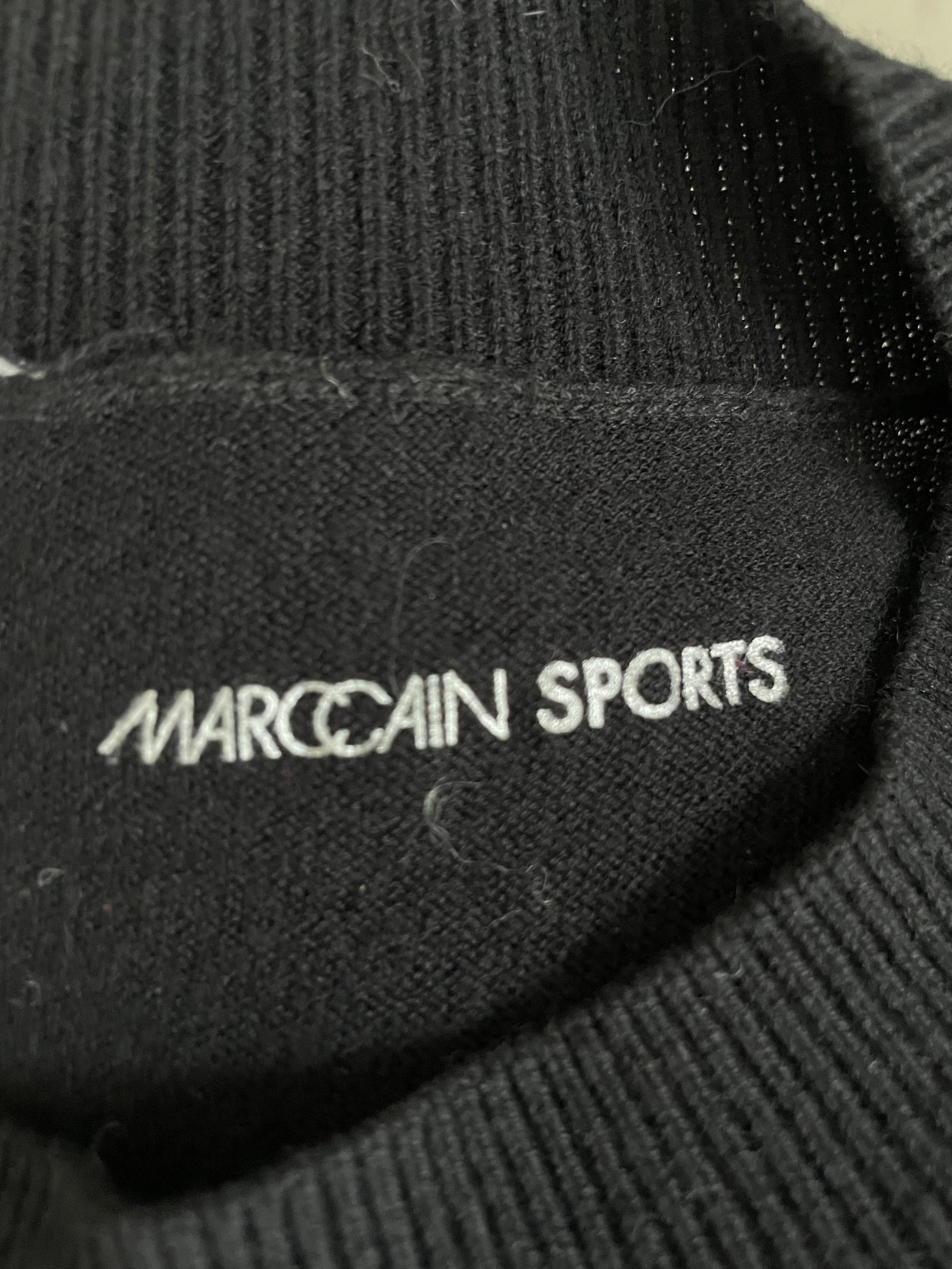 Detail view of the authentic Marc Cain branding label on the jumper, signifying premium German craftsmanship