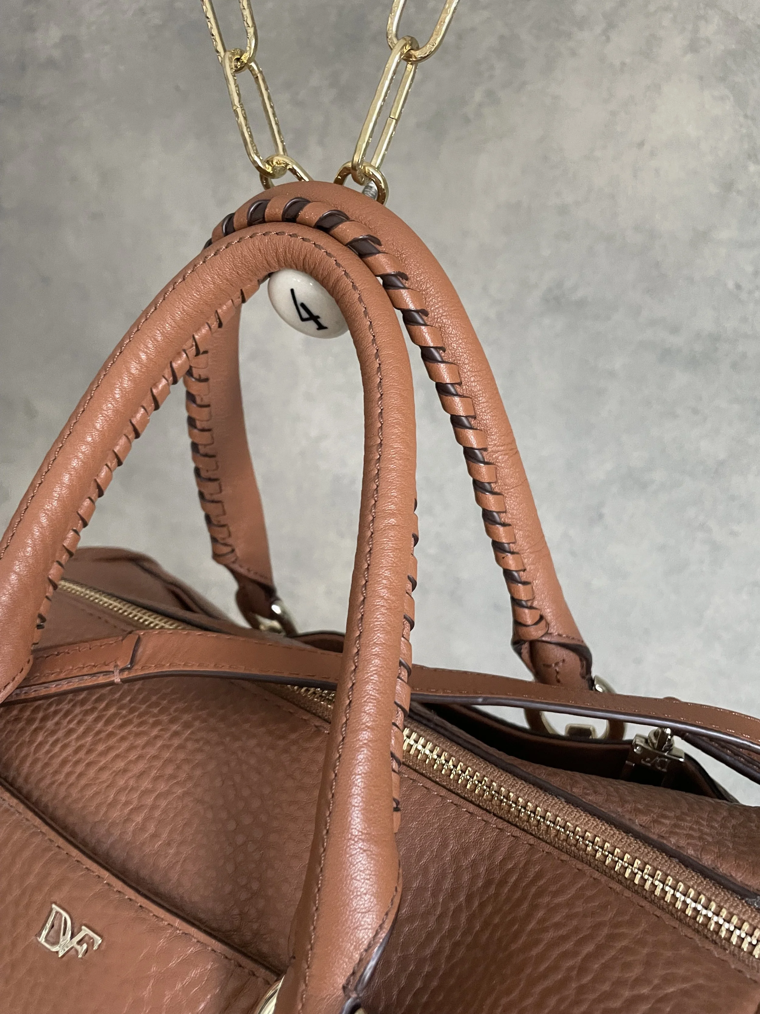 Close-up view of the braided leather detail on the handle of the DVF tote.