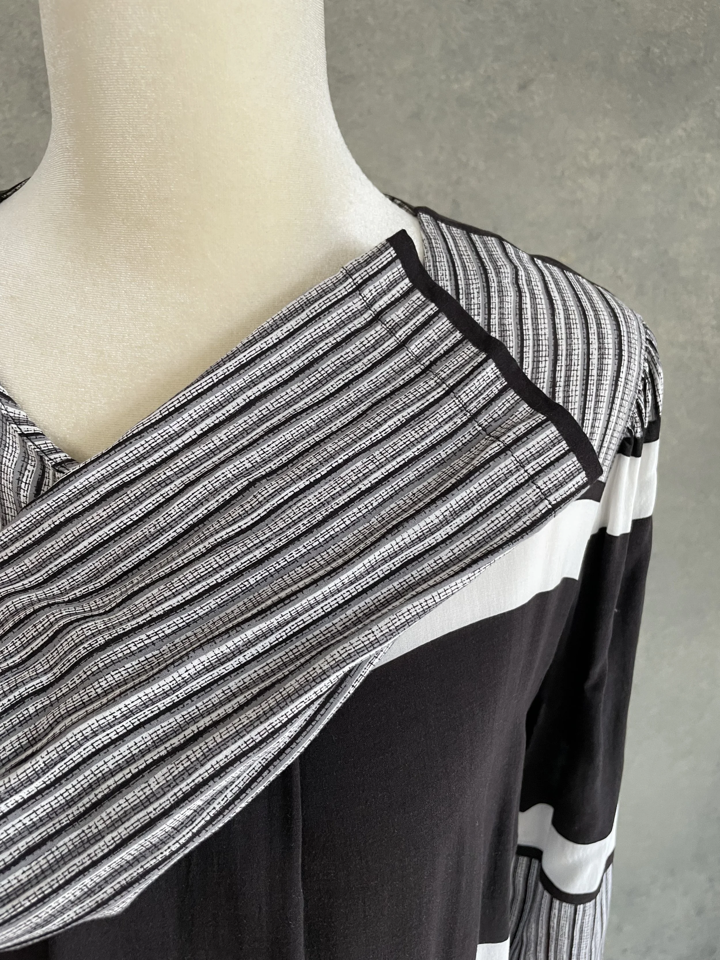 Close-up of the shoulder and neckline detail on a Rodebjer graphic black and white blouse, showing the striped fabric paneling.