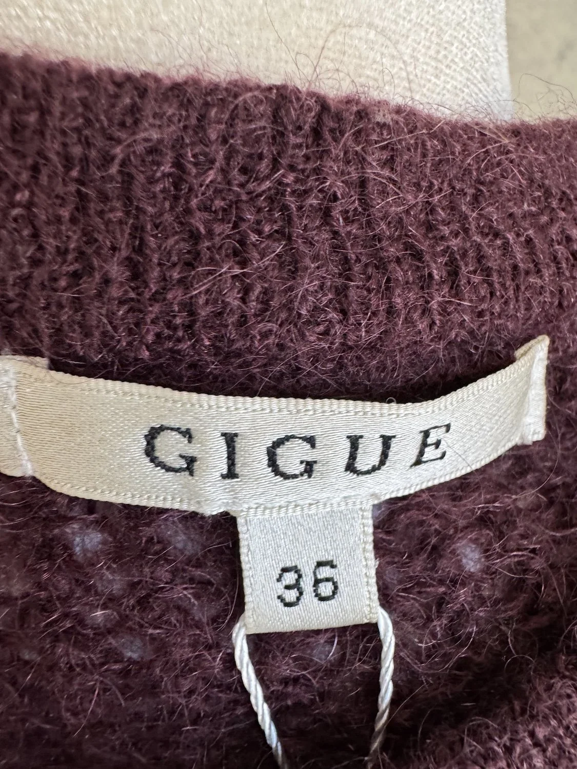 Nahaufnahme des eingenähten Nackenetiketts "GIGUE" mit darunterliegendem Größen-Etikett "36"