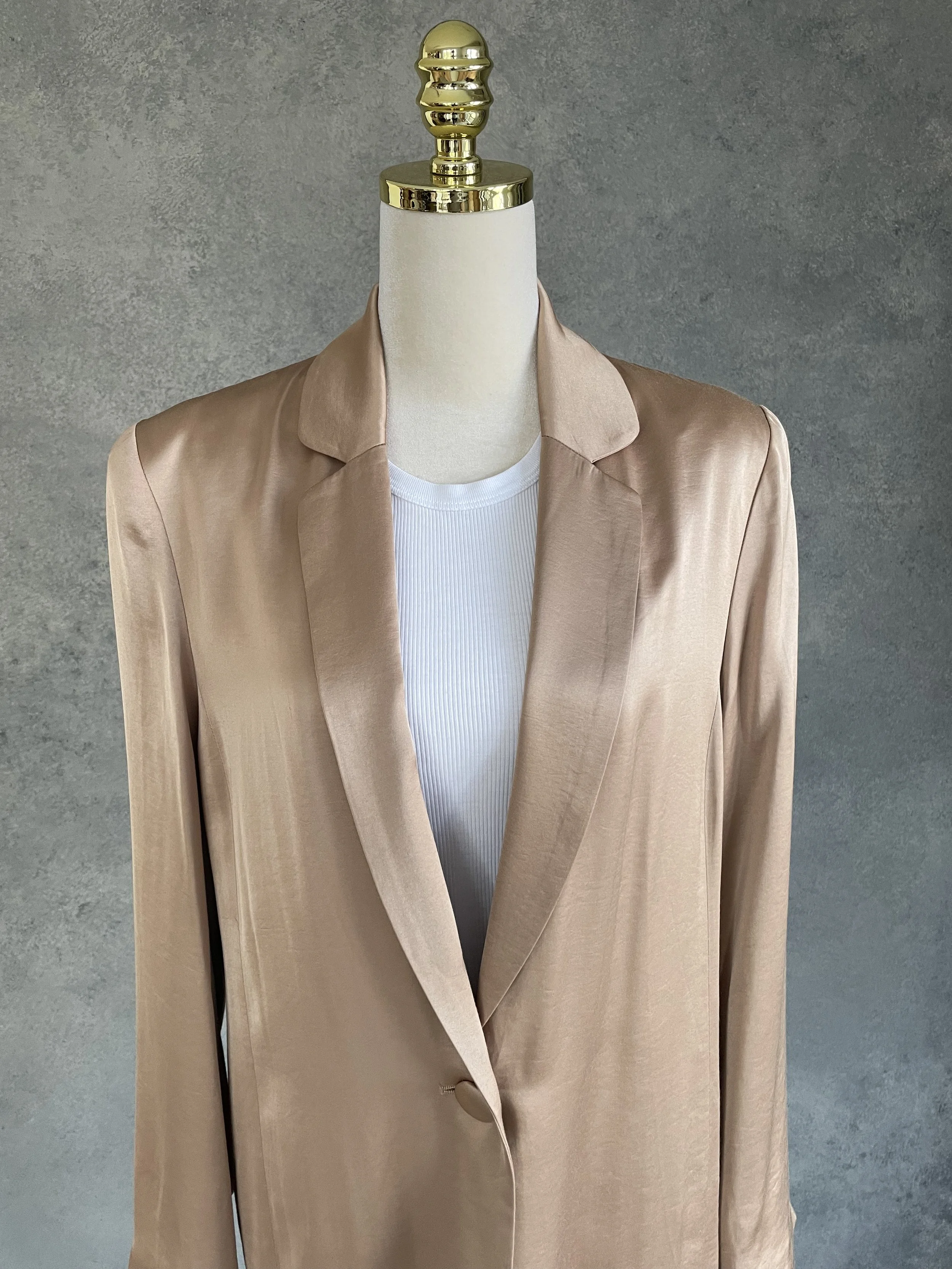 Close-up of the lapels and single-button closure of the golden blazer.