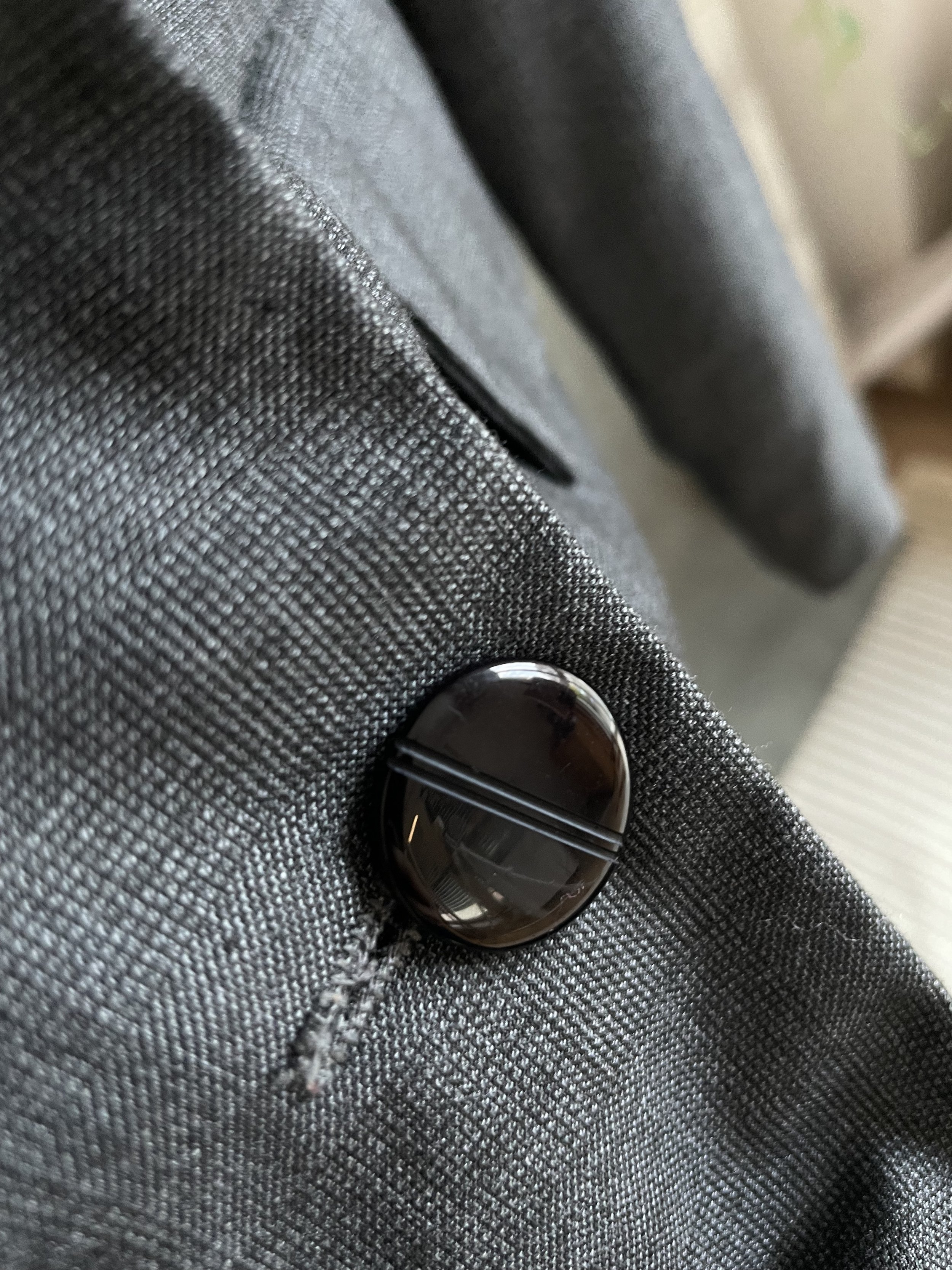 Macro close-up of one of the dark marbled buttons with a horizontal debossed line detail.