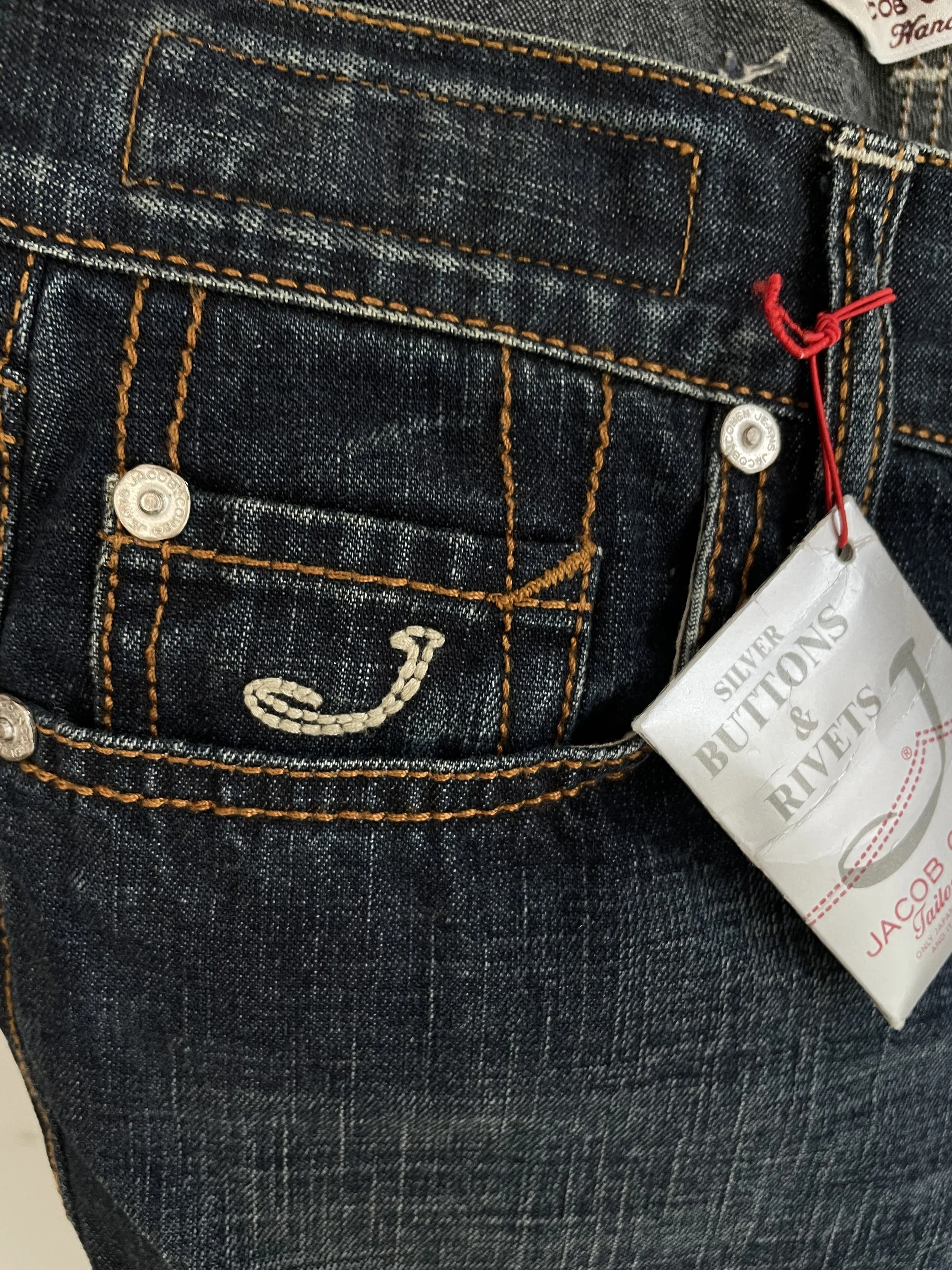 Focus shot of the Jacob Cohën metal hardware, button fly, and rivets on the dark blue NWT denim jeans.