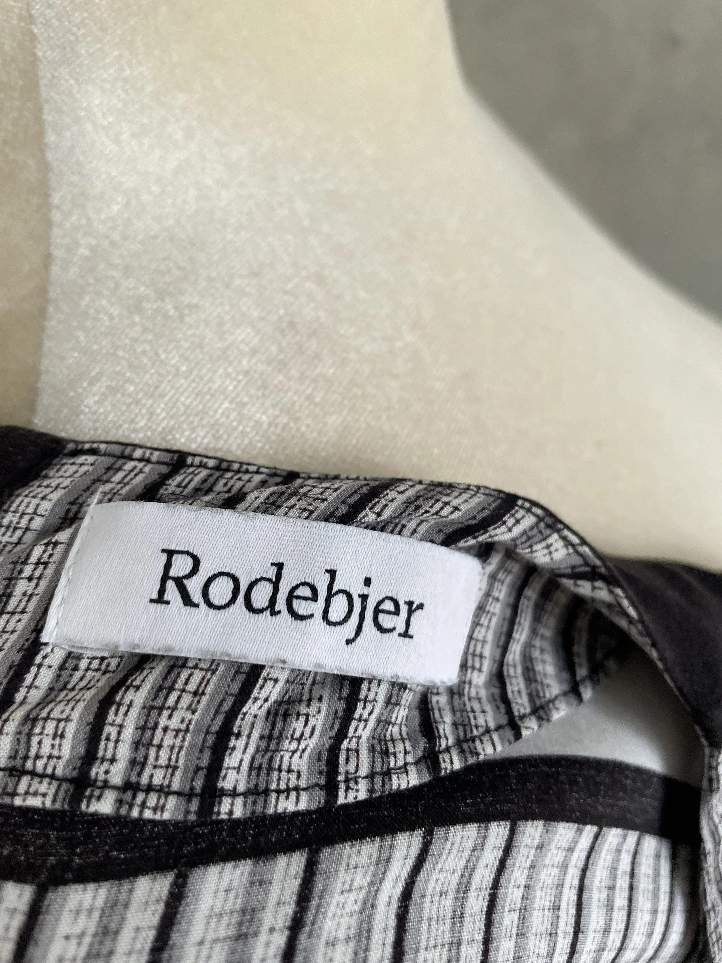 Close-up shot of the white "Rodebjer" brand label sewn into the inner neckline of the blouse.